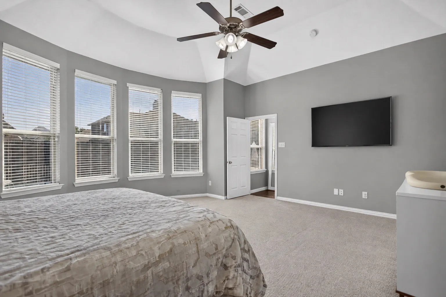 Tray ceiling with a ceiling fan light fixture, carpeted flooring, and multiple windows