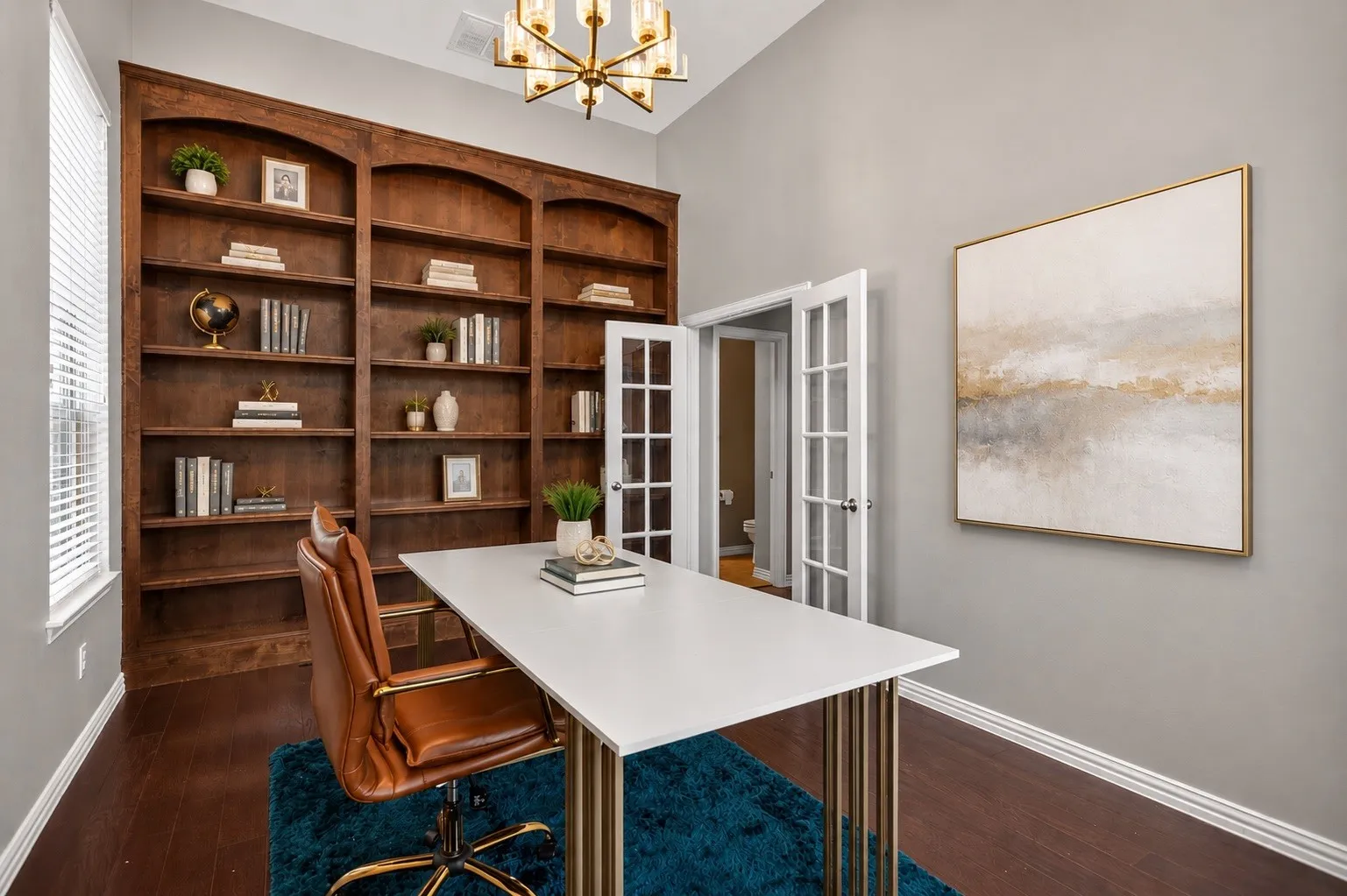 Built-in wood shelving, wood-finish flooring, and a contemporary chandelier