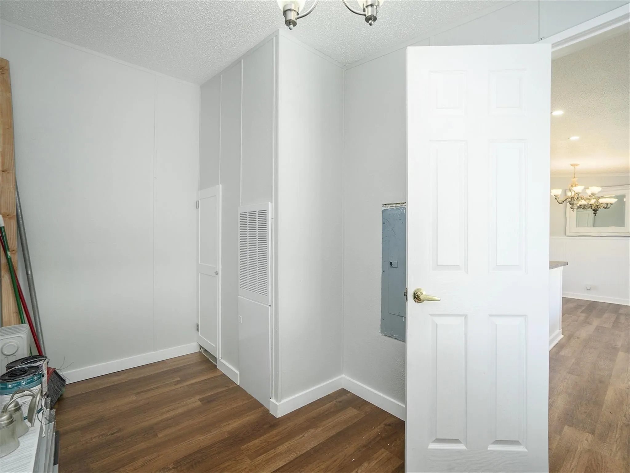 Corridor with a chandelier, a textured ceiling, dark wood-type flooring, and electric panel