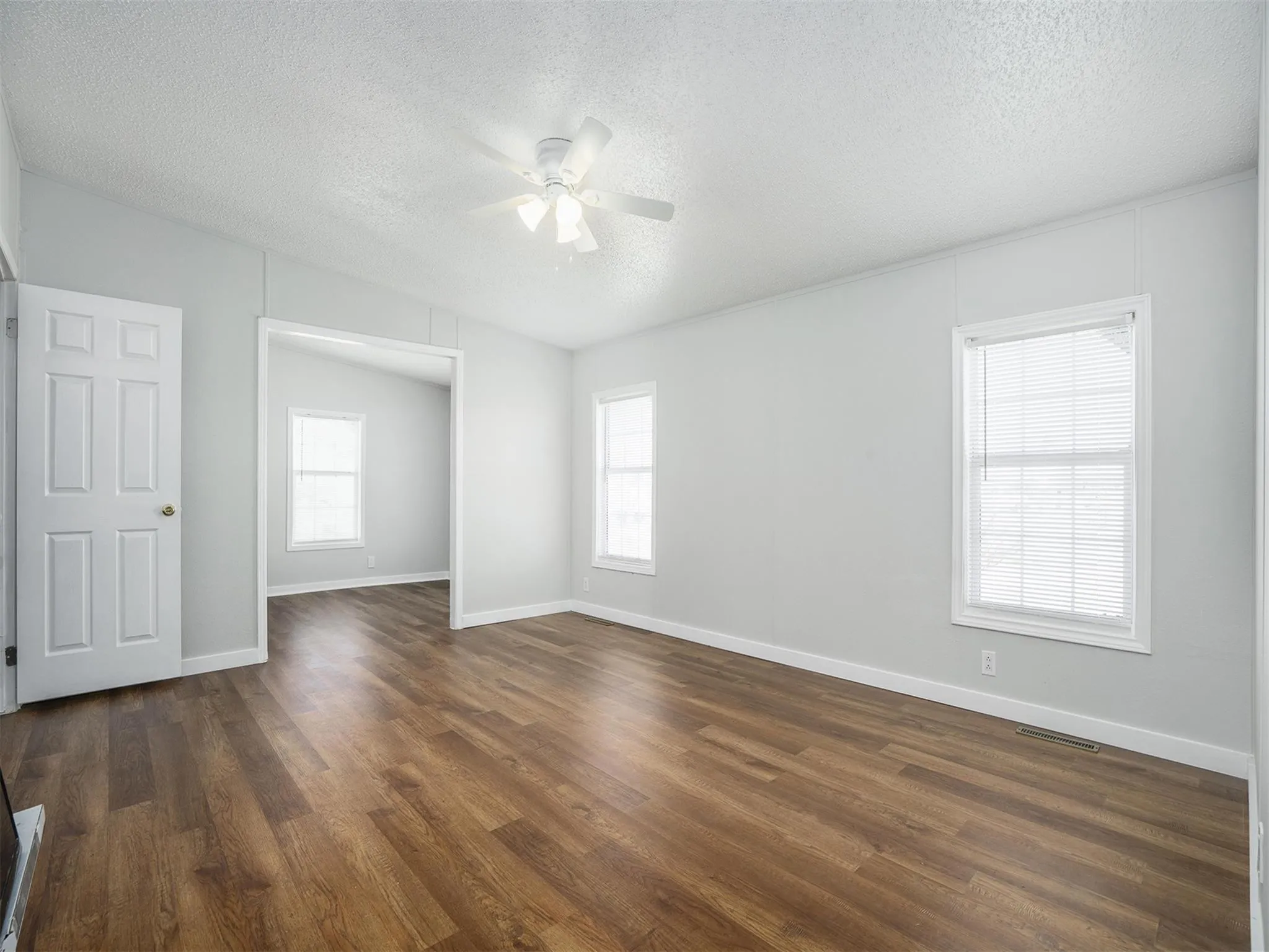 Empty room with dark wood-style floors, a textured ceiling, and ceiling fan