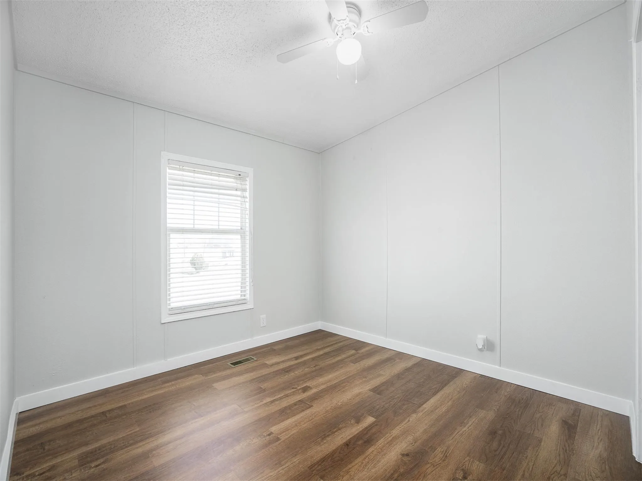 Spare room with a textured ceiling, dark wood-style flooring, and a ceiling fan