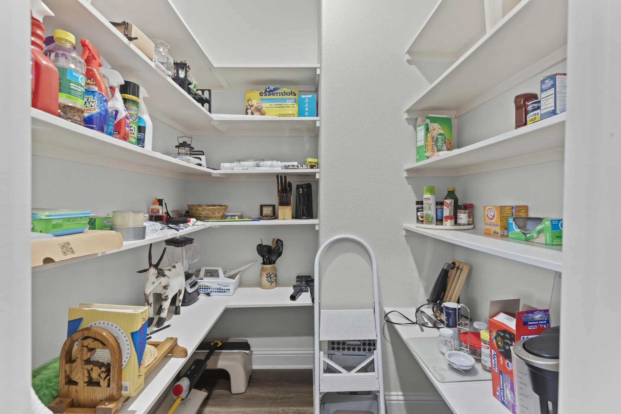 Walk-in pantry with extensive built-in shelving, white finish, and wood-finish flooring