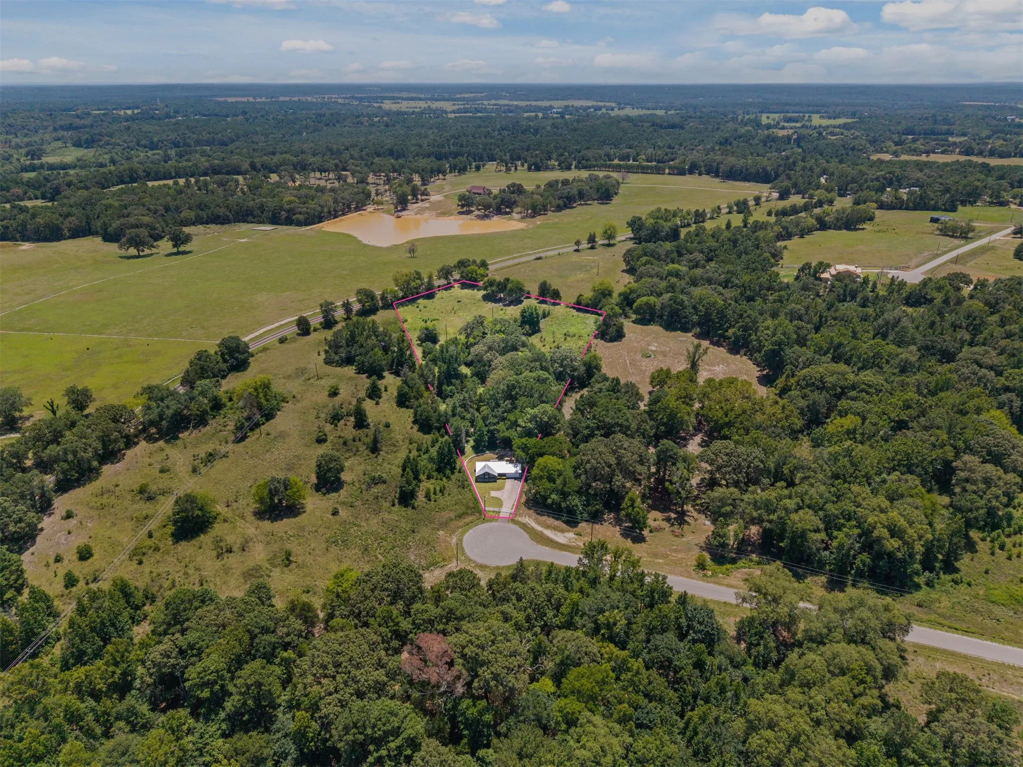 Expansive rural landscape featuring a private residence, mature tree cover, and open grassy areas