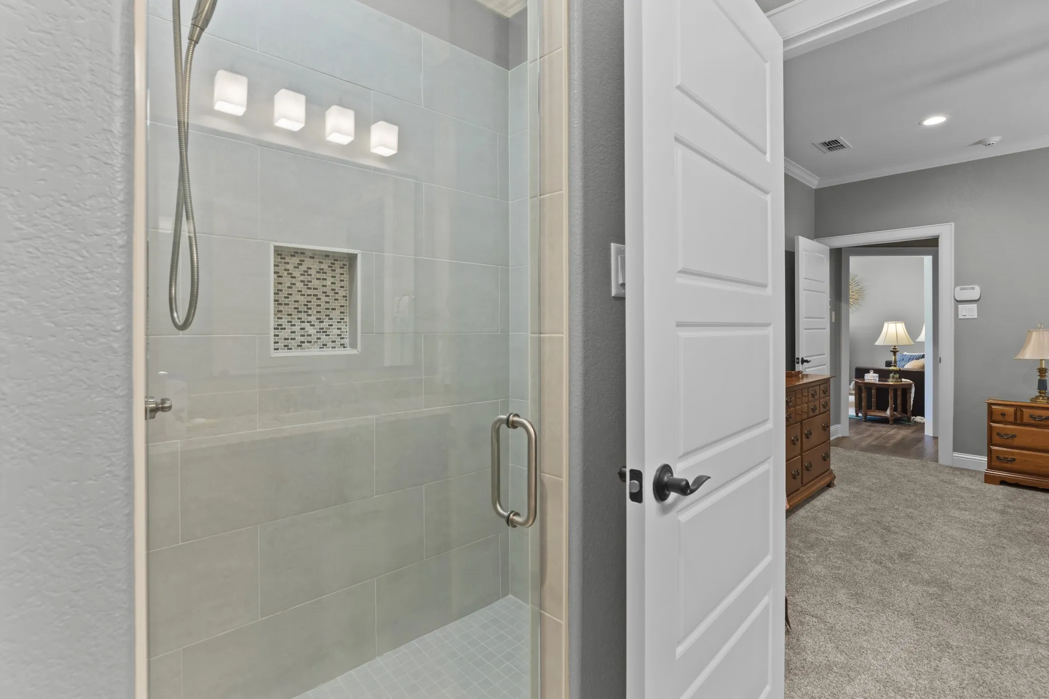 Glass-enclosed shower with subway tile surround, recessed niche, and contemporary light fixture