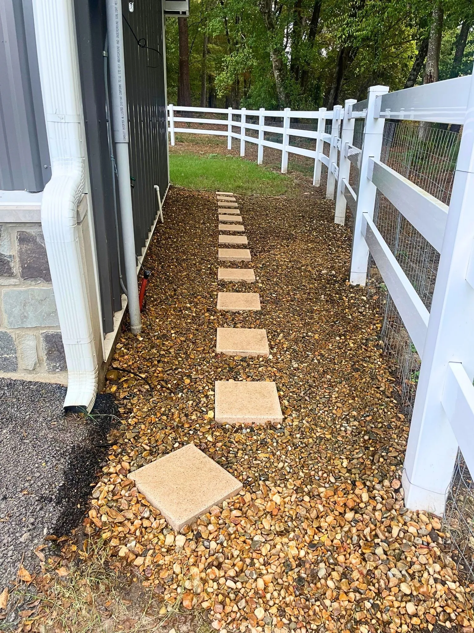 White picket fence, gravel pathway, stepping stones, dark siding, stone foundation