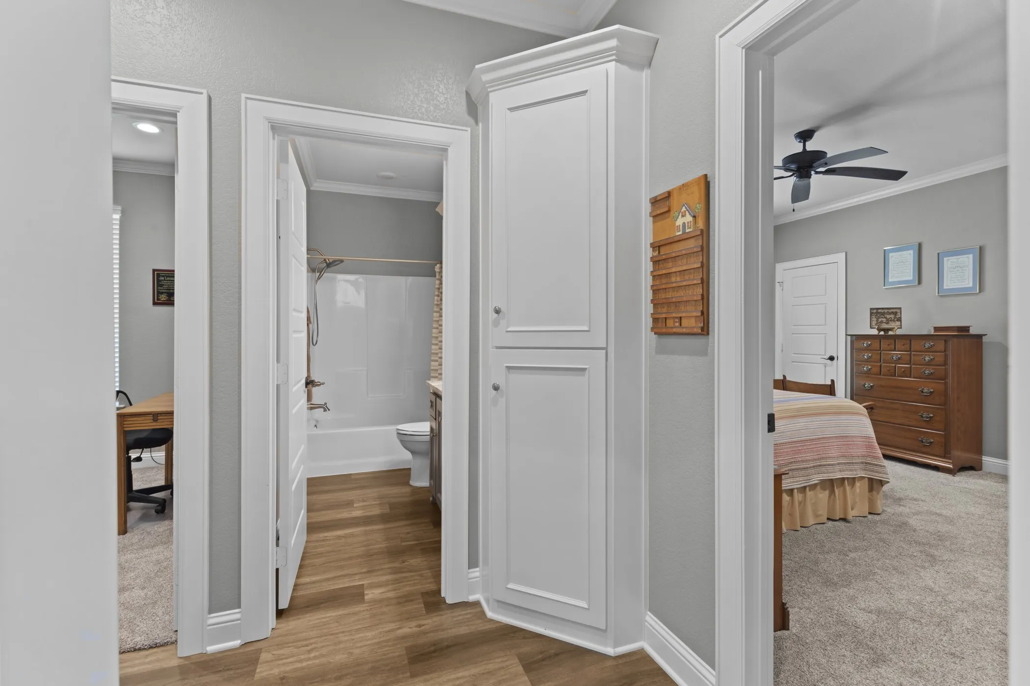 Hallway featuring wood-finish flooring, built-in white cabinetry, and crown molding