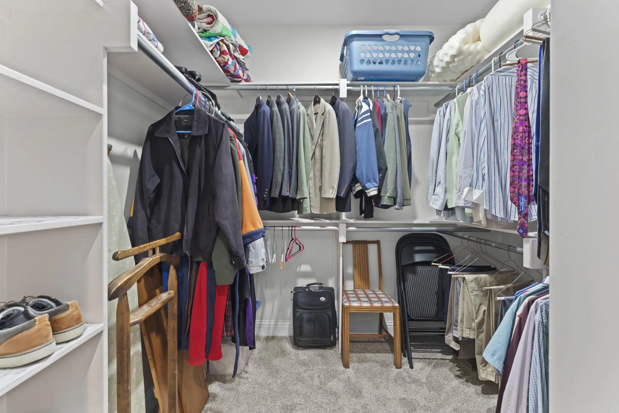 Integrated shelving system with multiple hanging rods, white built-in shelving, and light gray carpeting