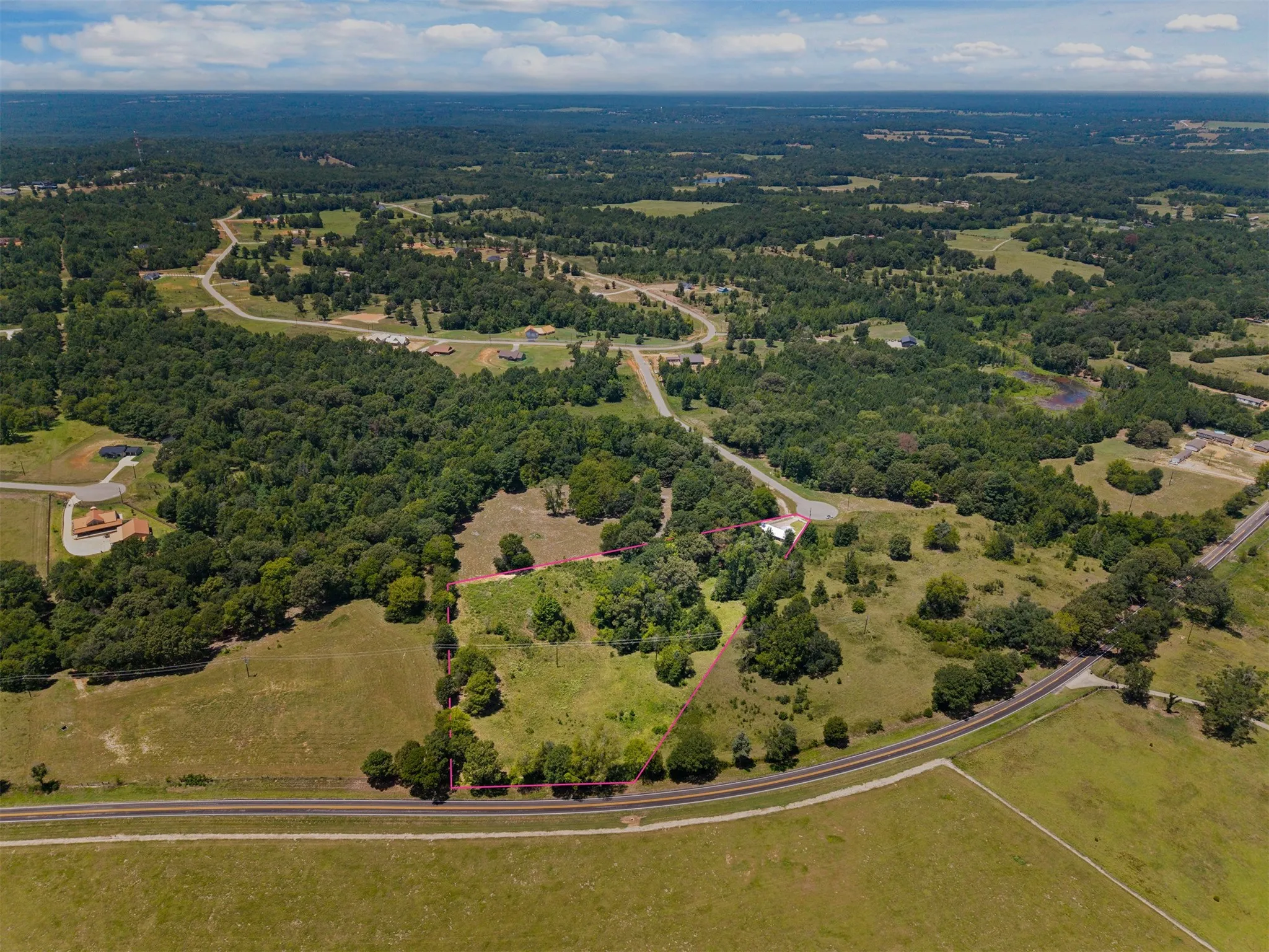 Expansive lot featuring mature trees, open grassland, and direct road frontage