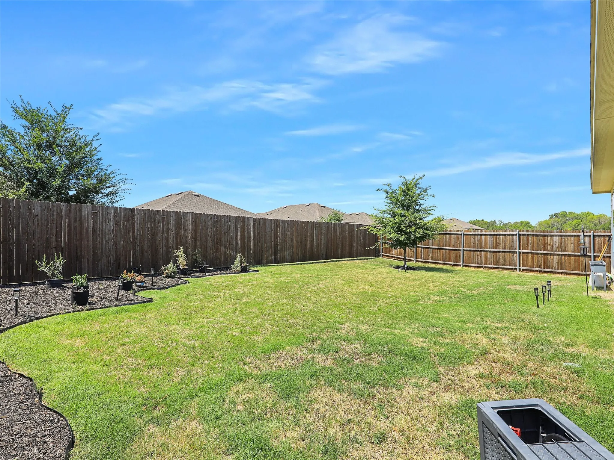 Beyond the porch is a large fenced backyard with plenty of open space.