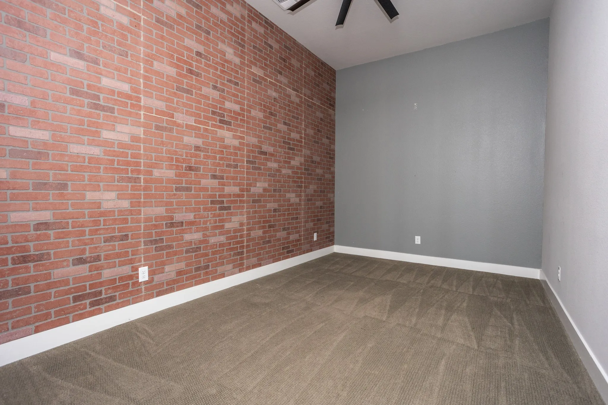 Textured accent wall, neutral tone carpeting, painted walls, ceiling fan, and white trim