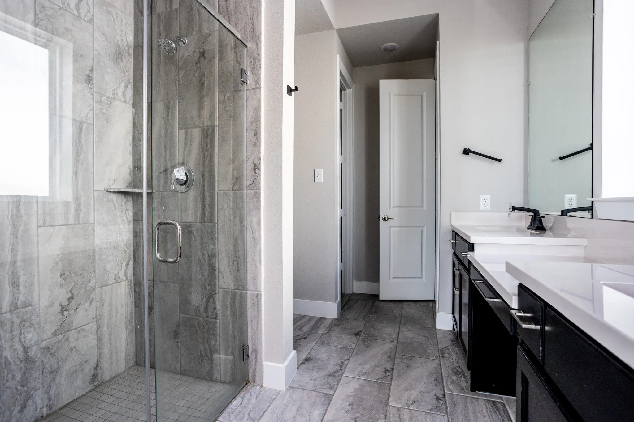 Glass-enclosed shower with gray tiled walls and a built-in shelf