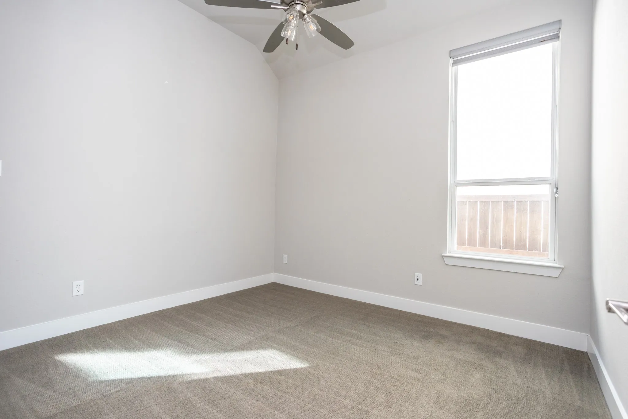 Carpeted room featuring a vaulted ceiling and a ceiling fan