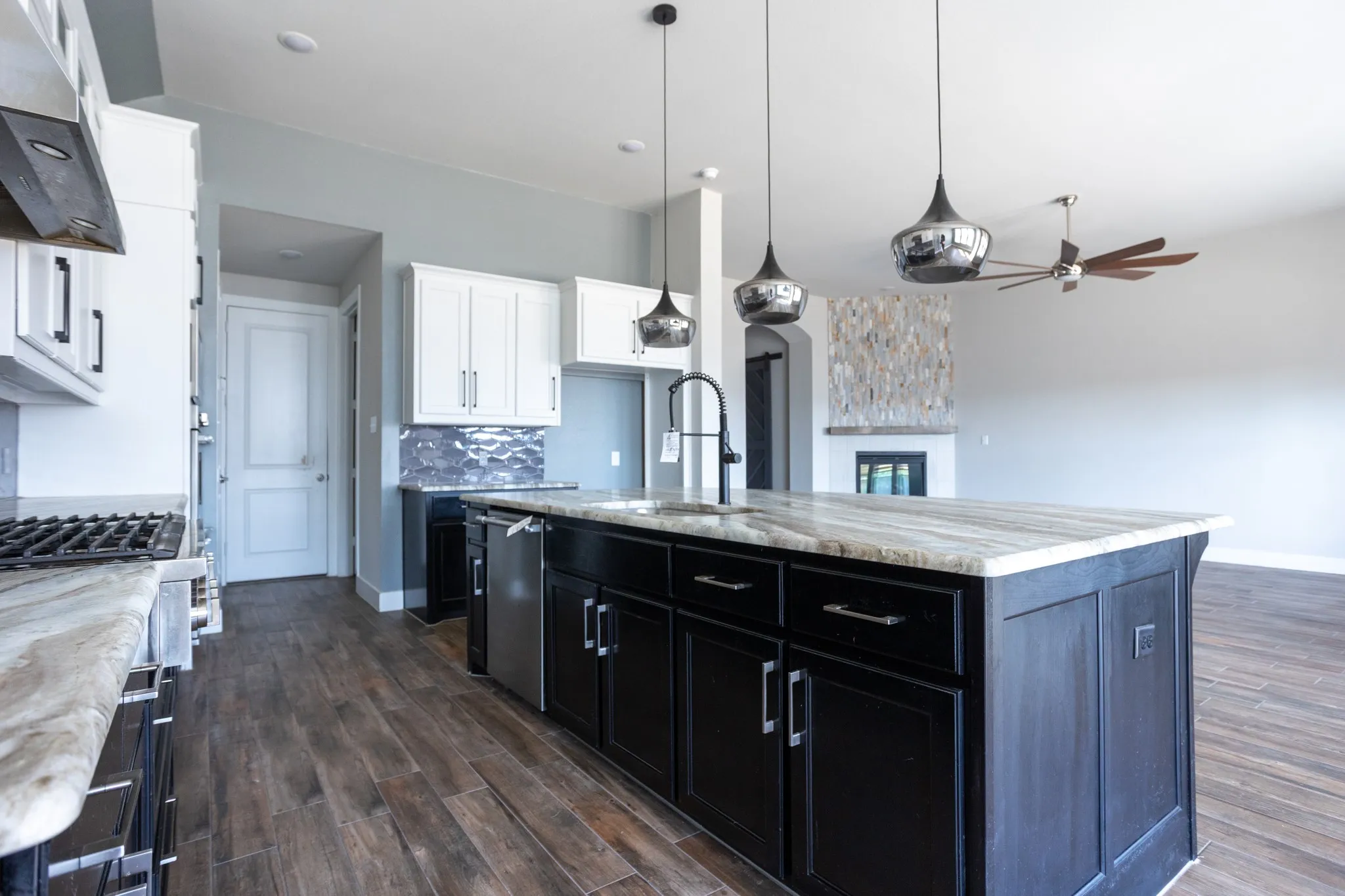 Expansive kitchen island with a stone countertop, featuring a built-in sink and pendant lighting