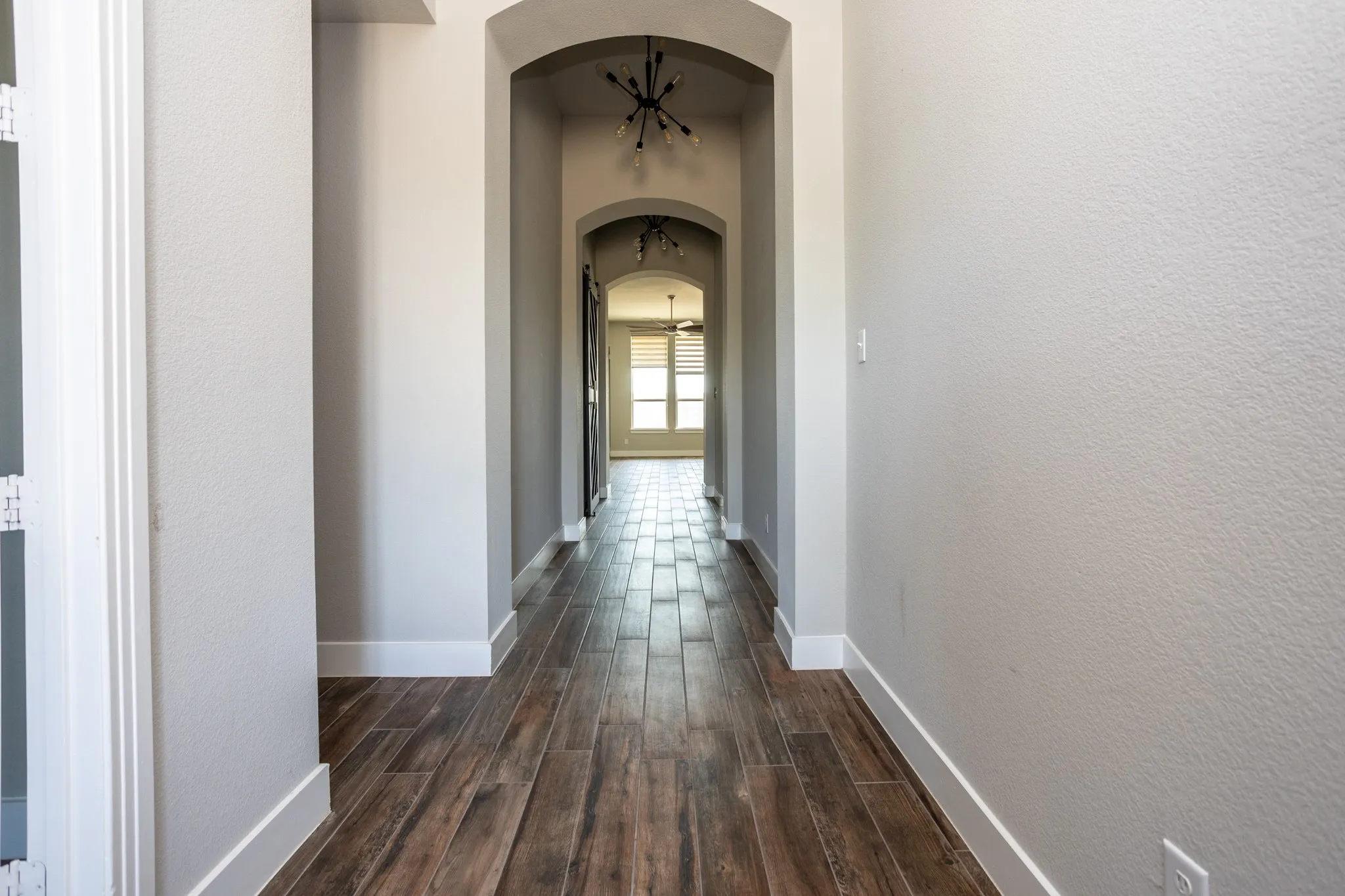 Arched doorways, wood-finish flooring, and contemporary overhead lighting fixtures