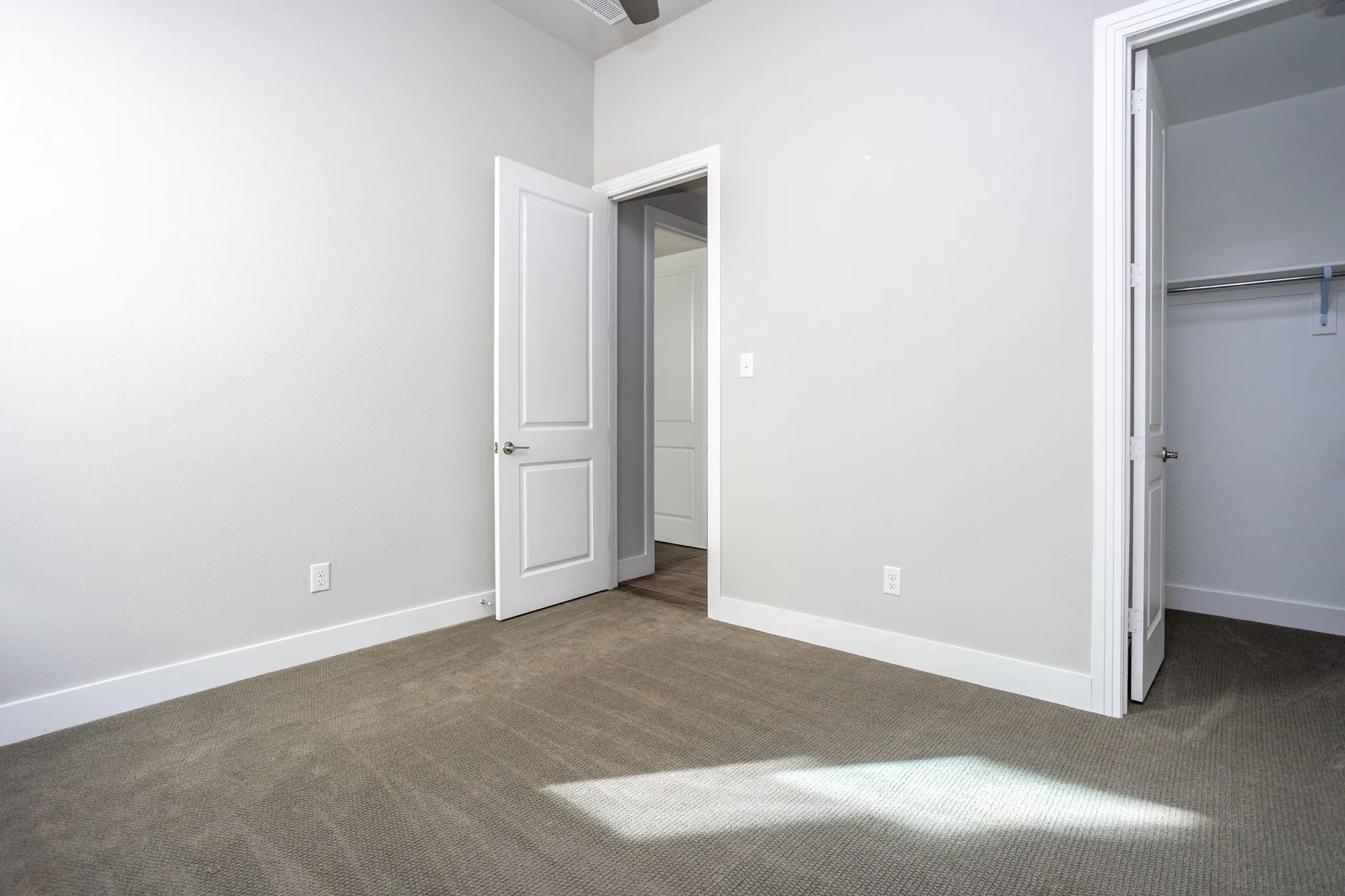 Neutral wall paint, carpet flooring, a closet with a hanging rod, and a ceiling fan