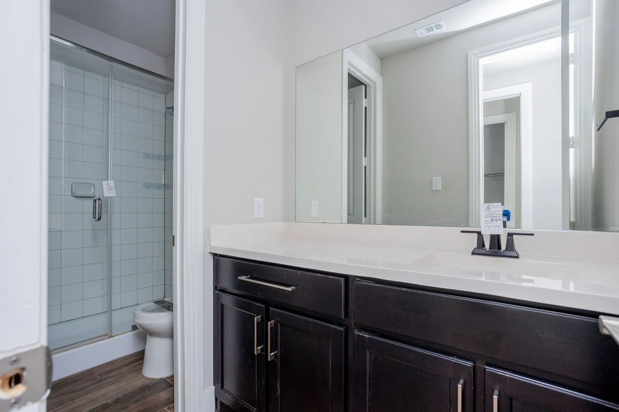 Bathroom featuring a dark wood-finish vanity with a light-colored countertop, integrated sink, and a framed mirror
