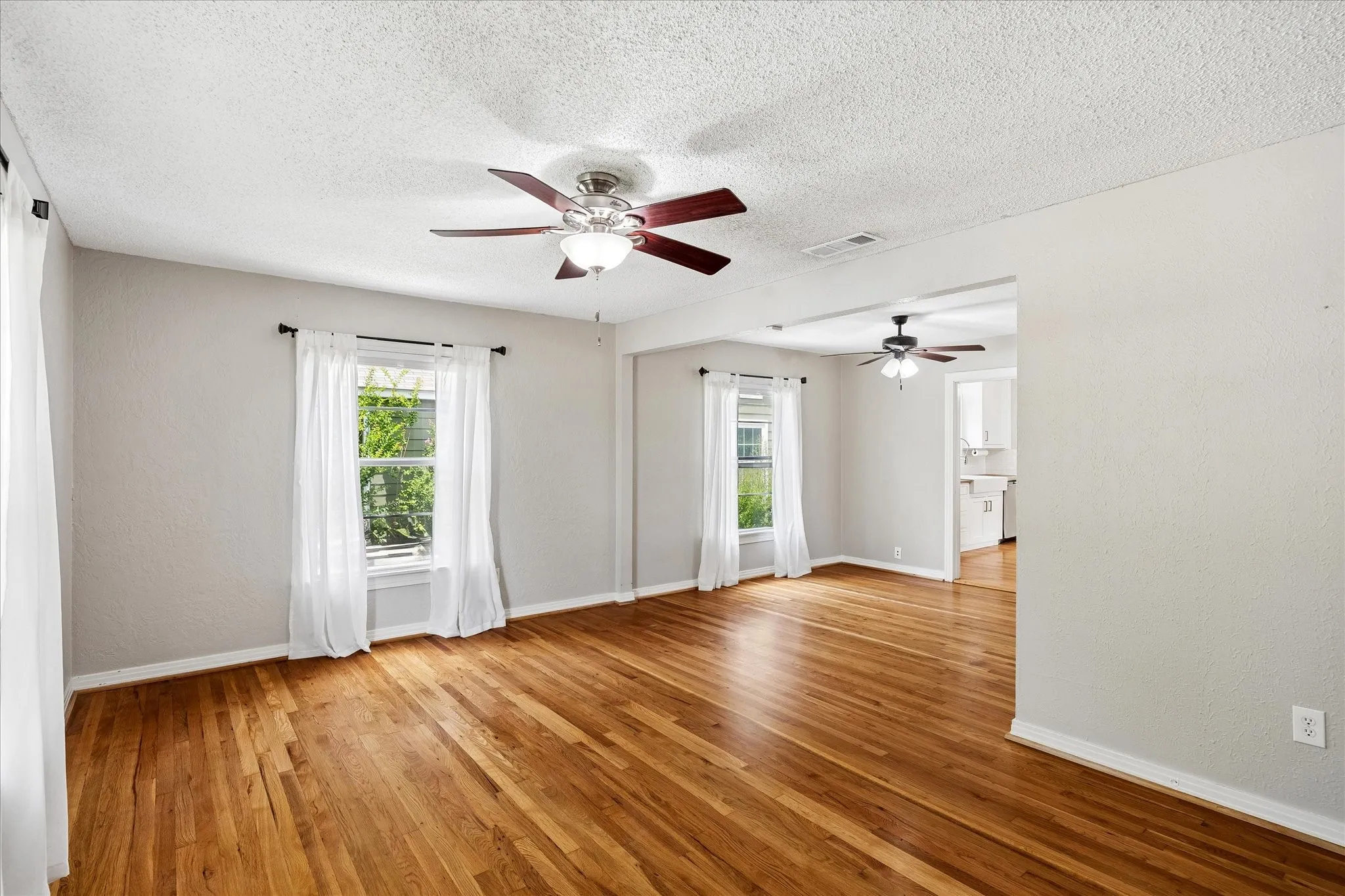 Hardwood flooring throughout, multiple windows, two ceiling fans, and light-toned walls