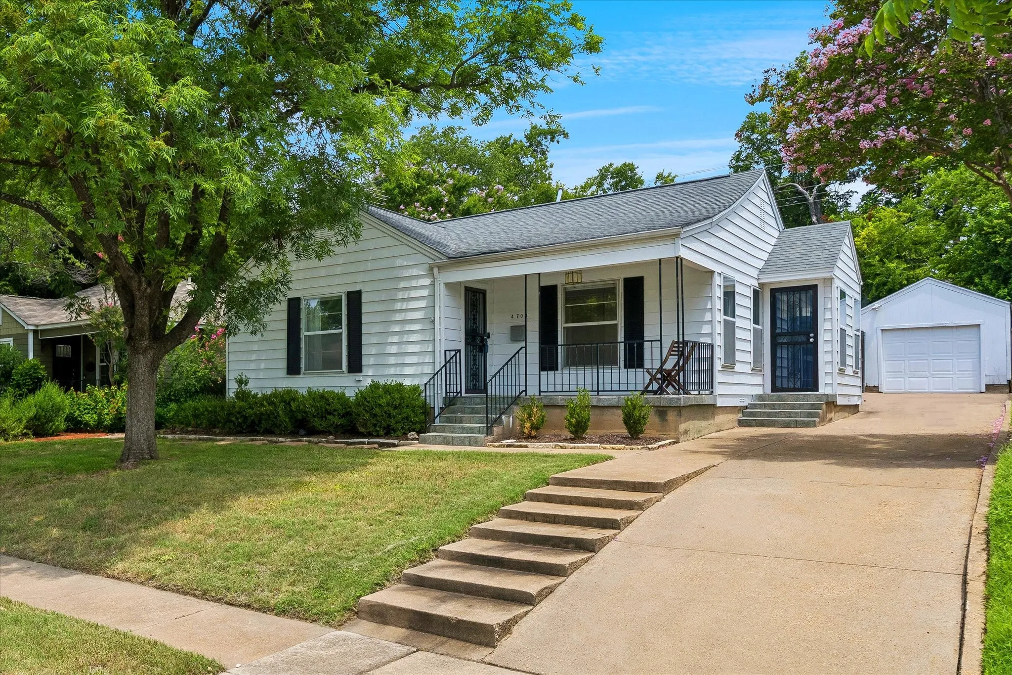 Single-story residence featuring white siding, a covered porch, and a detached garage