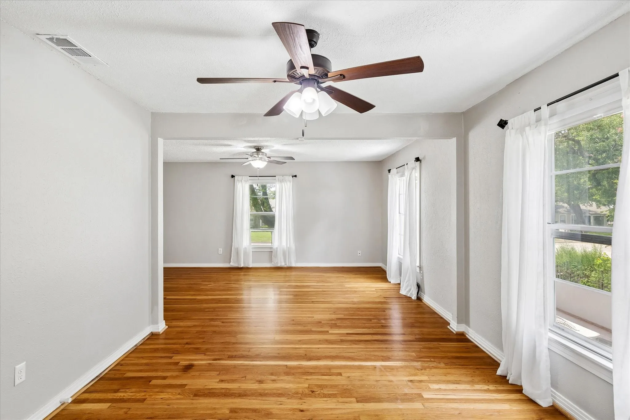 Hardwood flooring and multiple windows with sheer curtains
