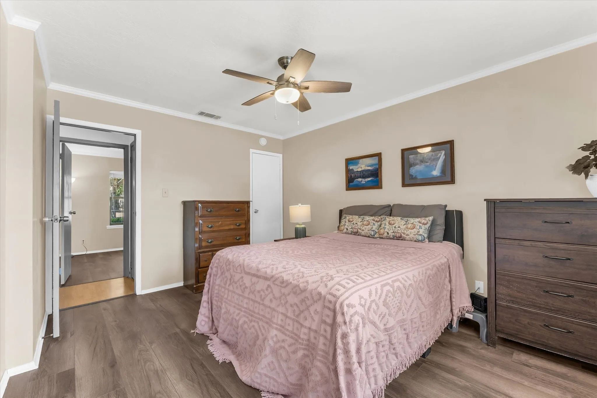 Wood-finish flooring throughout, complemented by crown molding and a ceiling fan