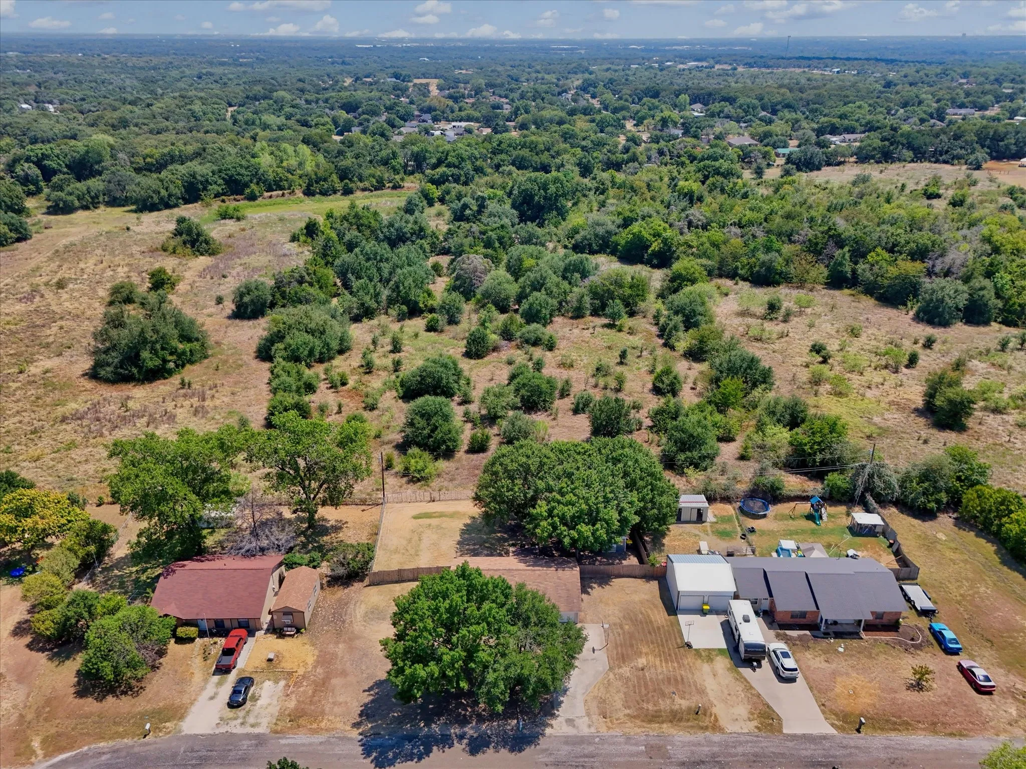 Expansive land parcel featuring existing residential structures, mature trees, and natural vegetation