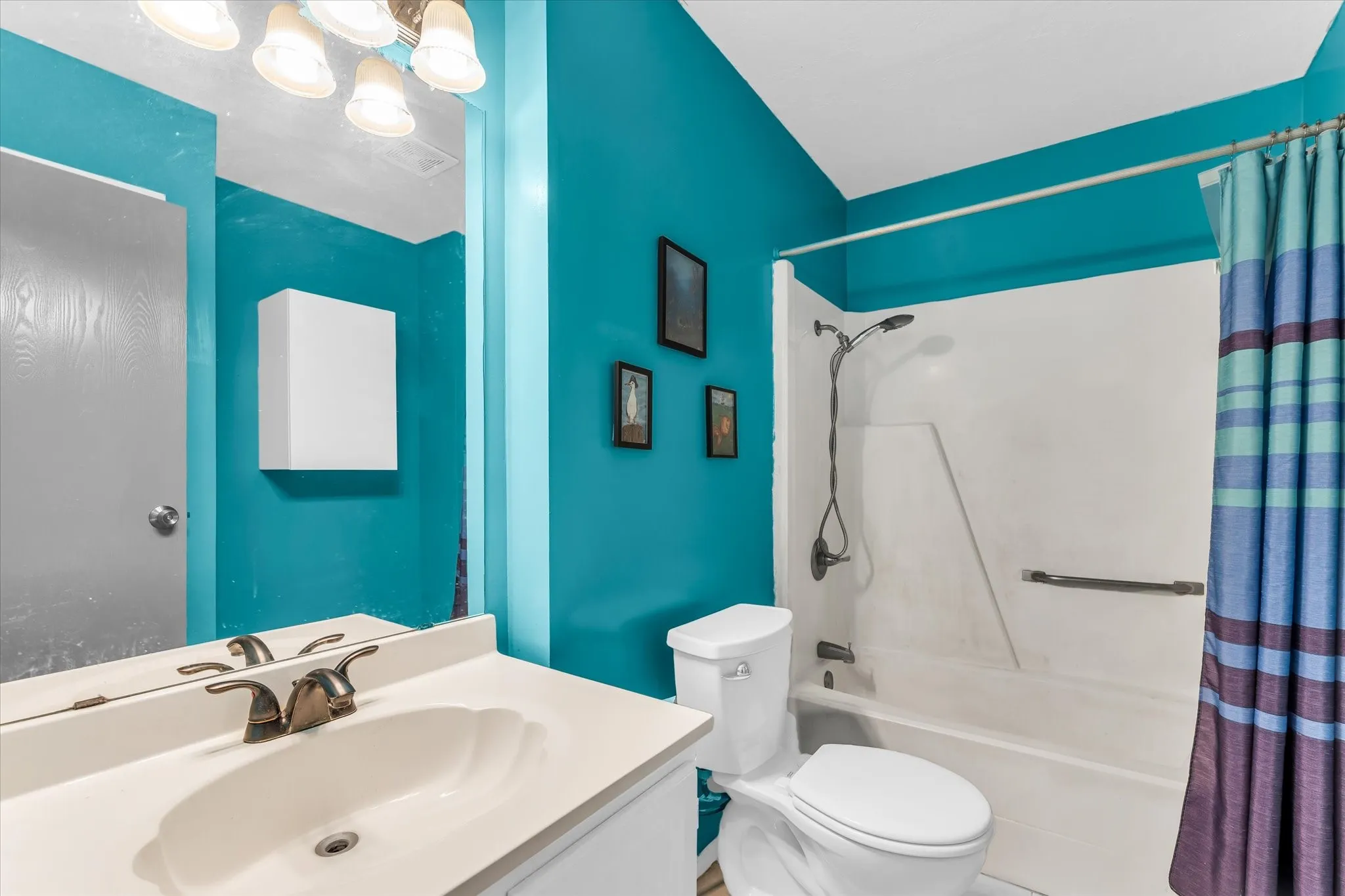 White vanity with integrated sink, bronze-finish faucet, and overhead lighting