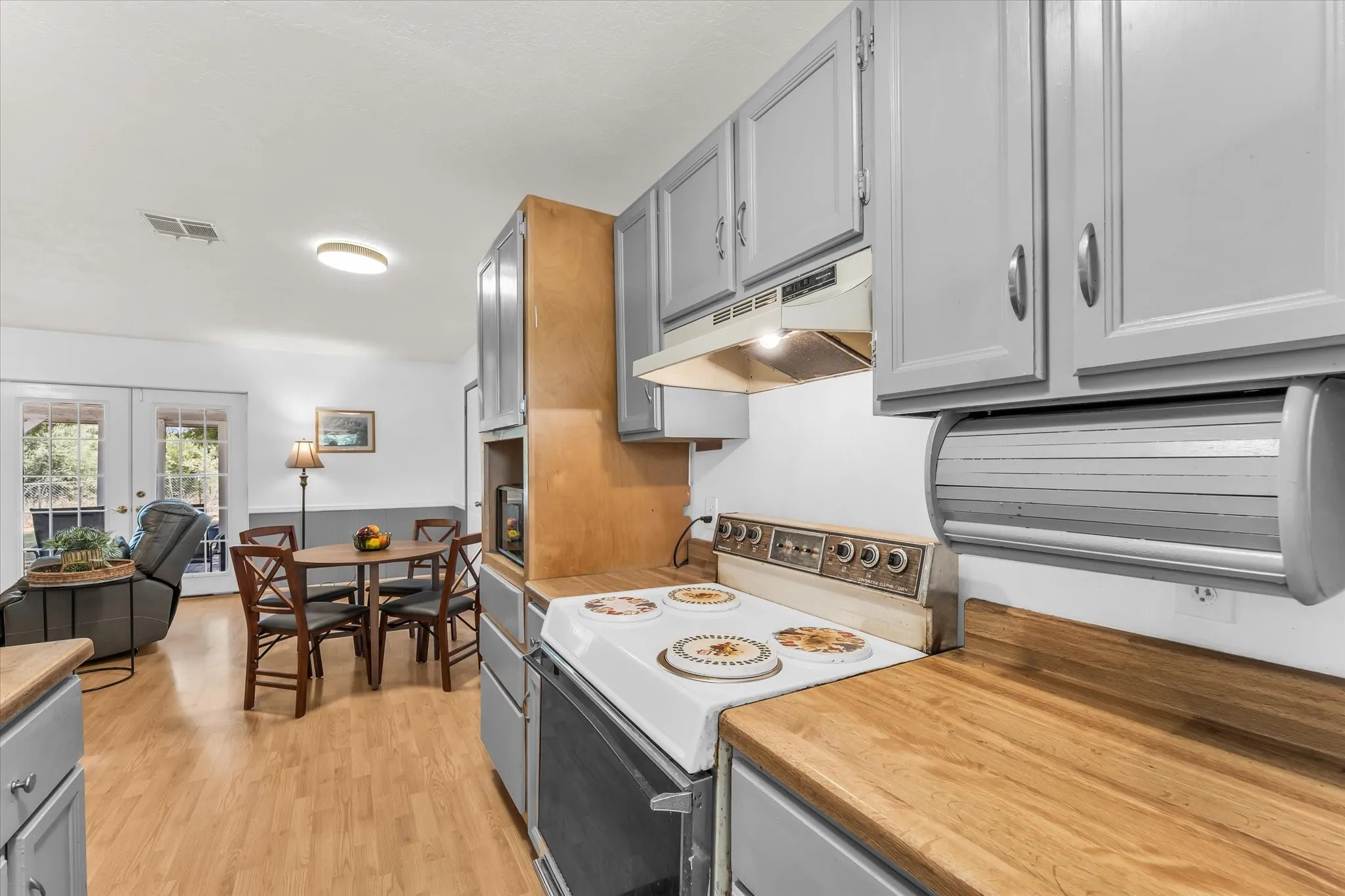 Kitchen featuring wood-finish countertops, grey cabinetry, and an electric range