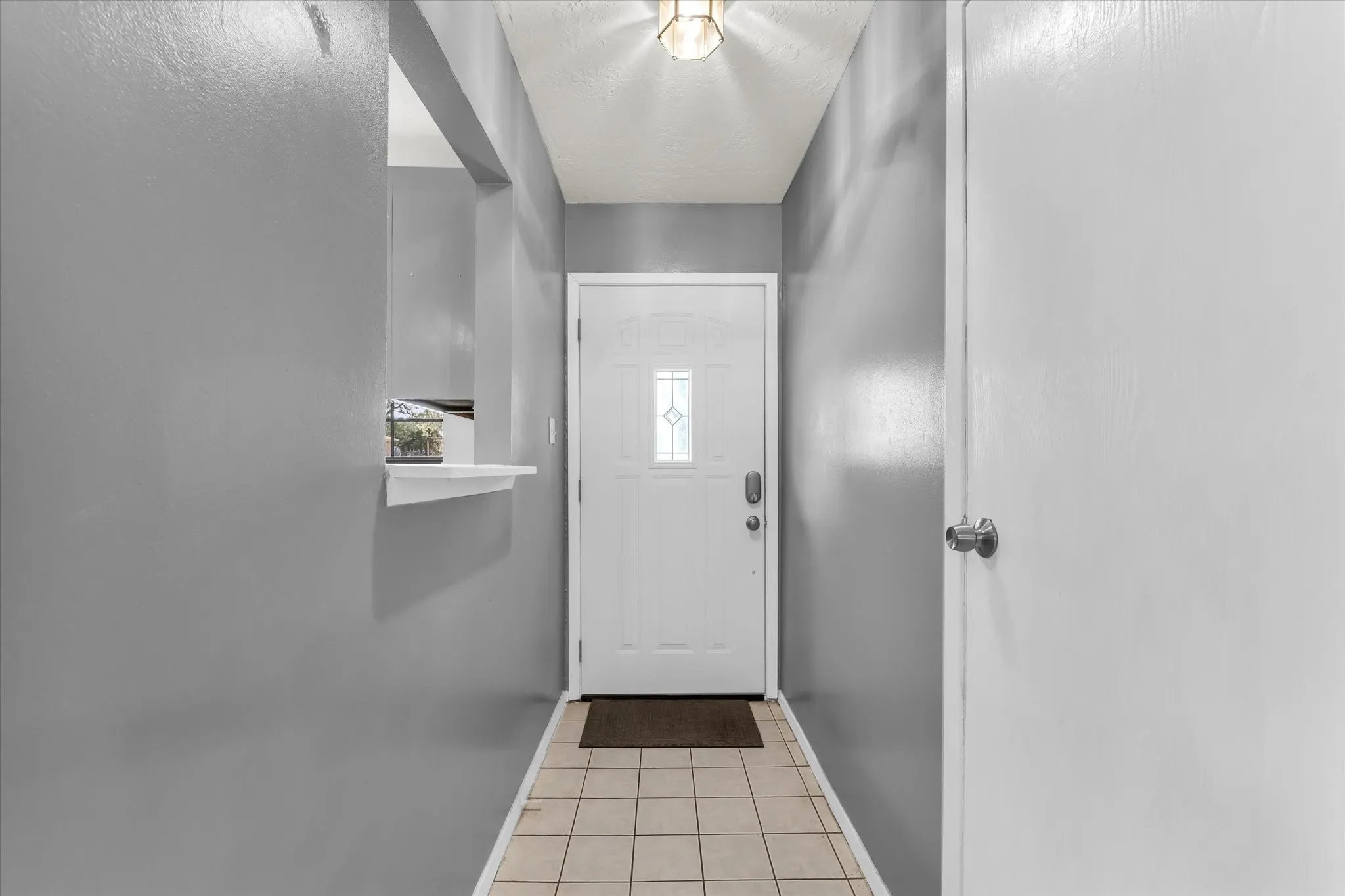 Entryway featuring a white door with decorative glass inserts, recessed lighting, and tile flooring