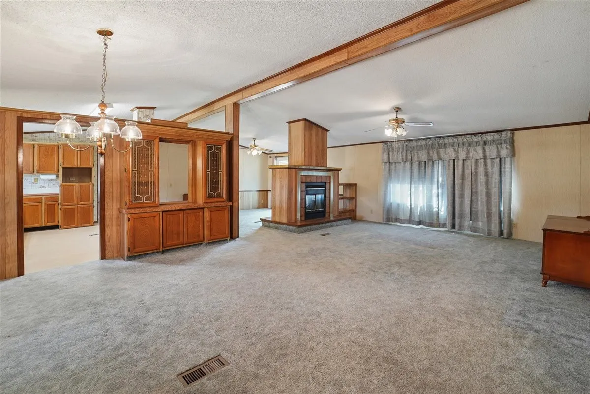 Built-in display cabinetry, wood-paneled fireplace with hearth, and ceiling fan