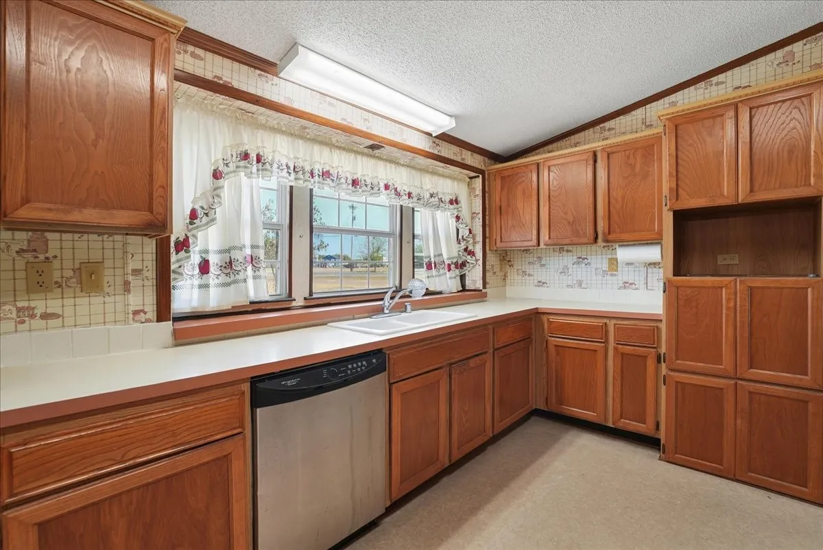 Wood-finish cabinetry with extensive storage, dual-basin stainless steel sink, and light-colored countertops