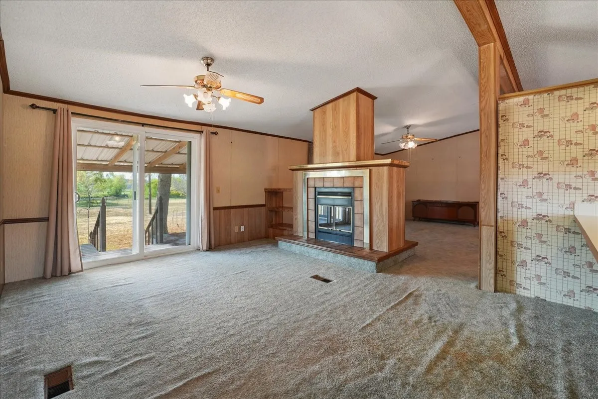 Living area with a built-in fireplace featuring a brick surround, wood paneling, and a raised hearth
