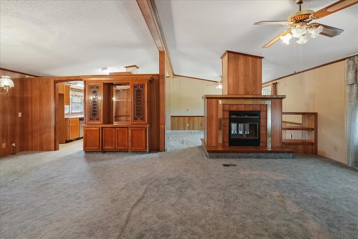 Wood-paneled accent walls, built-in display cabinetry, a fireplace with a tiled hearth, and integrated shelving