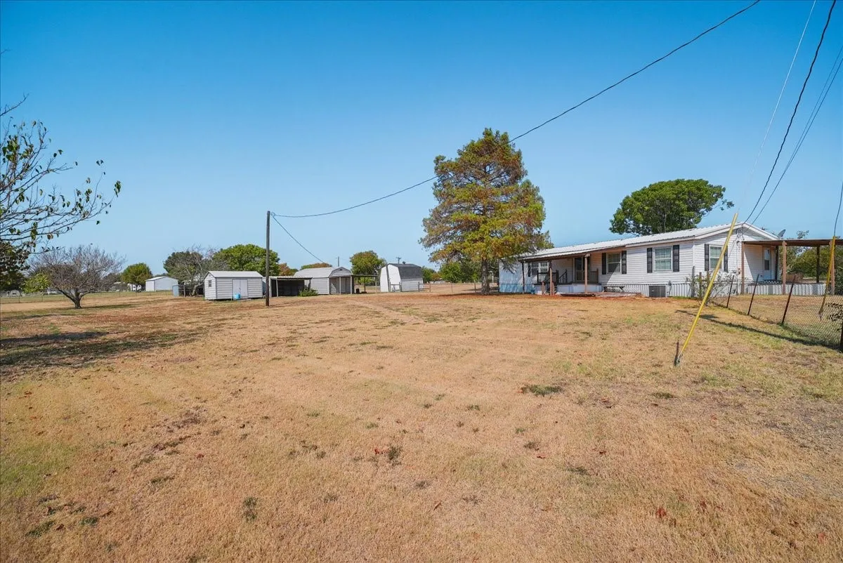 Expansive lot with a single-story residence, multiple outbuildings, and mature trees