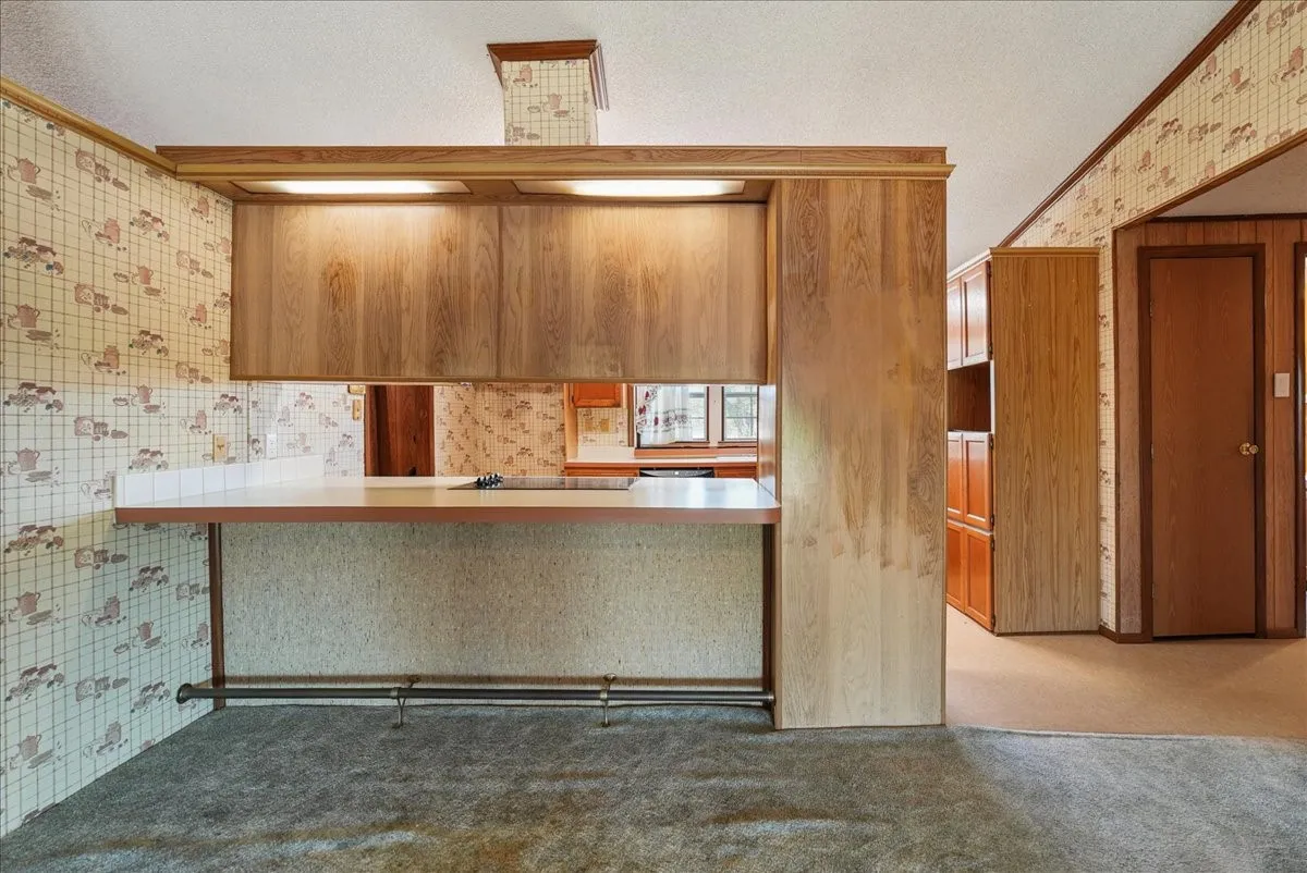 Built-in bar with overhead cabinetry, integrated lighting, and a foot rail