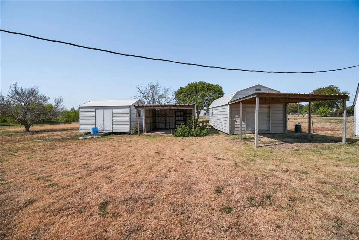 Two metal storage sheds, one with an attached covered structure