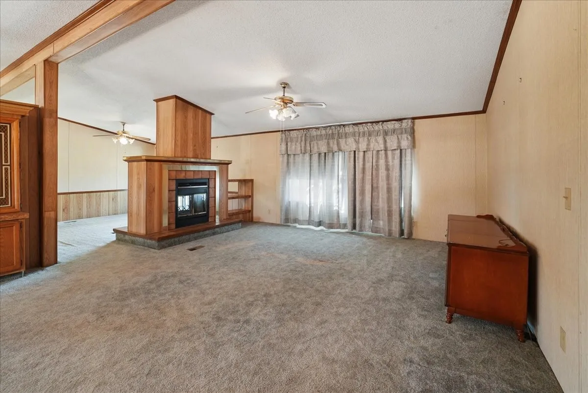 Central fireplace with wood-finish surround and hearth, integrated shelving, and ceiling fans