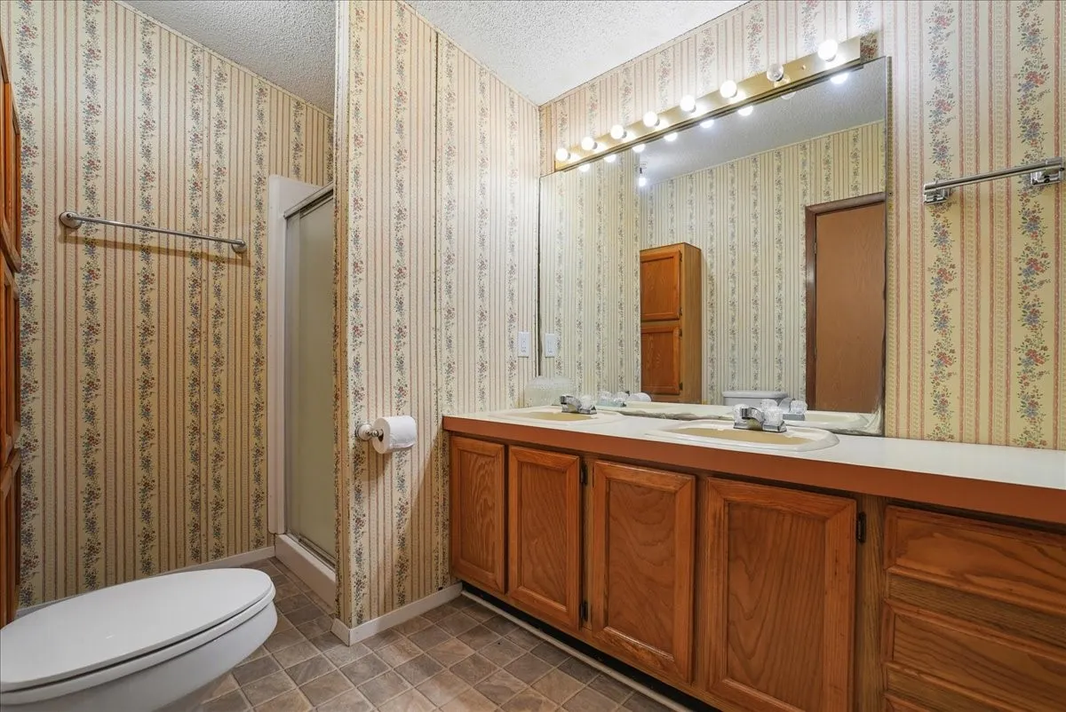 Dual vanity with integrated sinks, wood-finish cabinetry, and overhead bar lighting