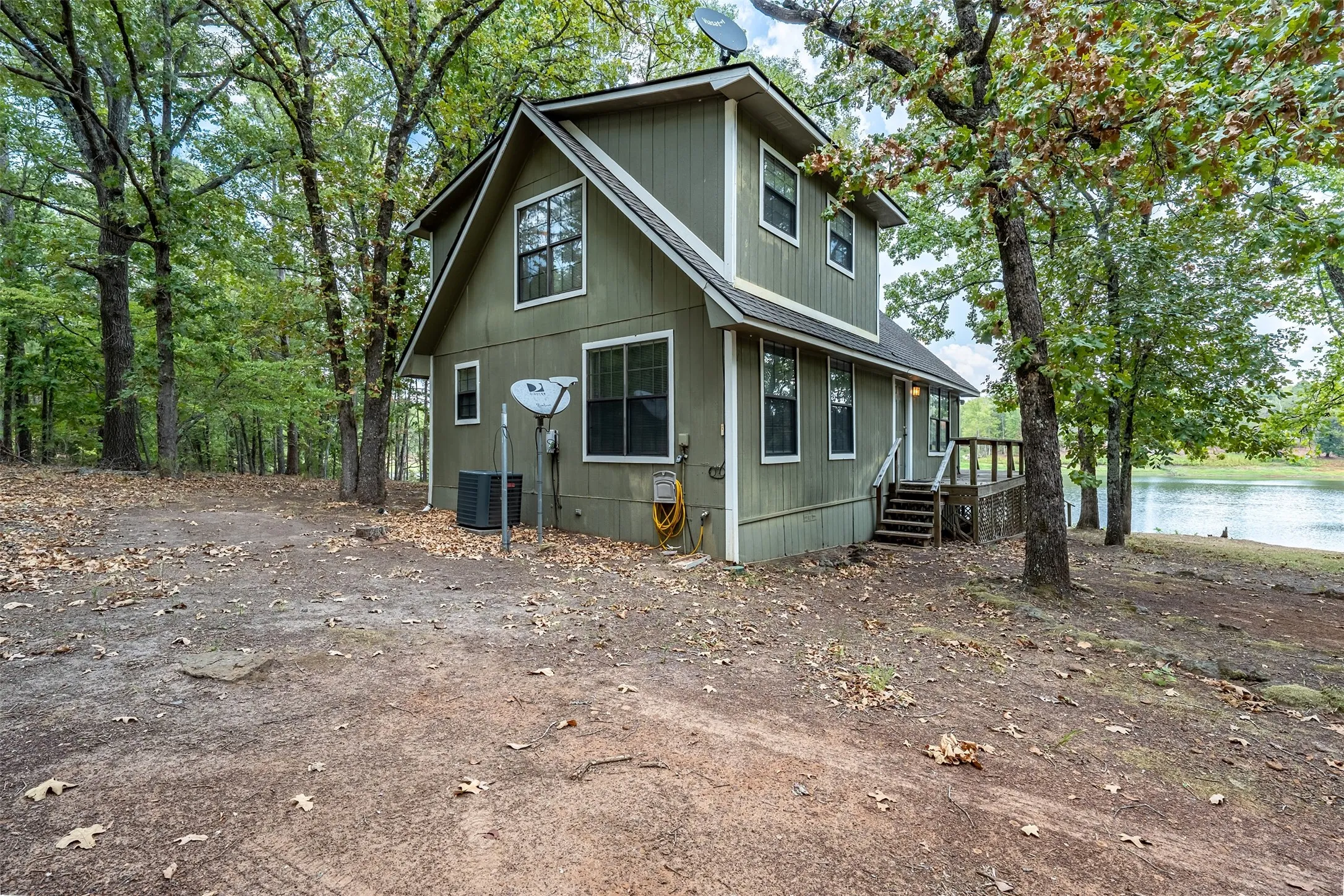 Two-story exterior with horizontal siding, multiple windows, a wooden deck, and direct lake access