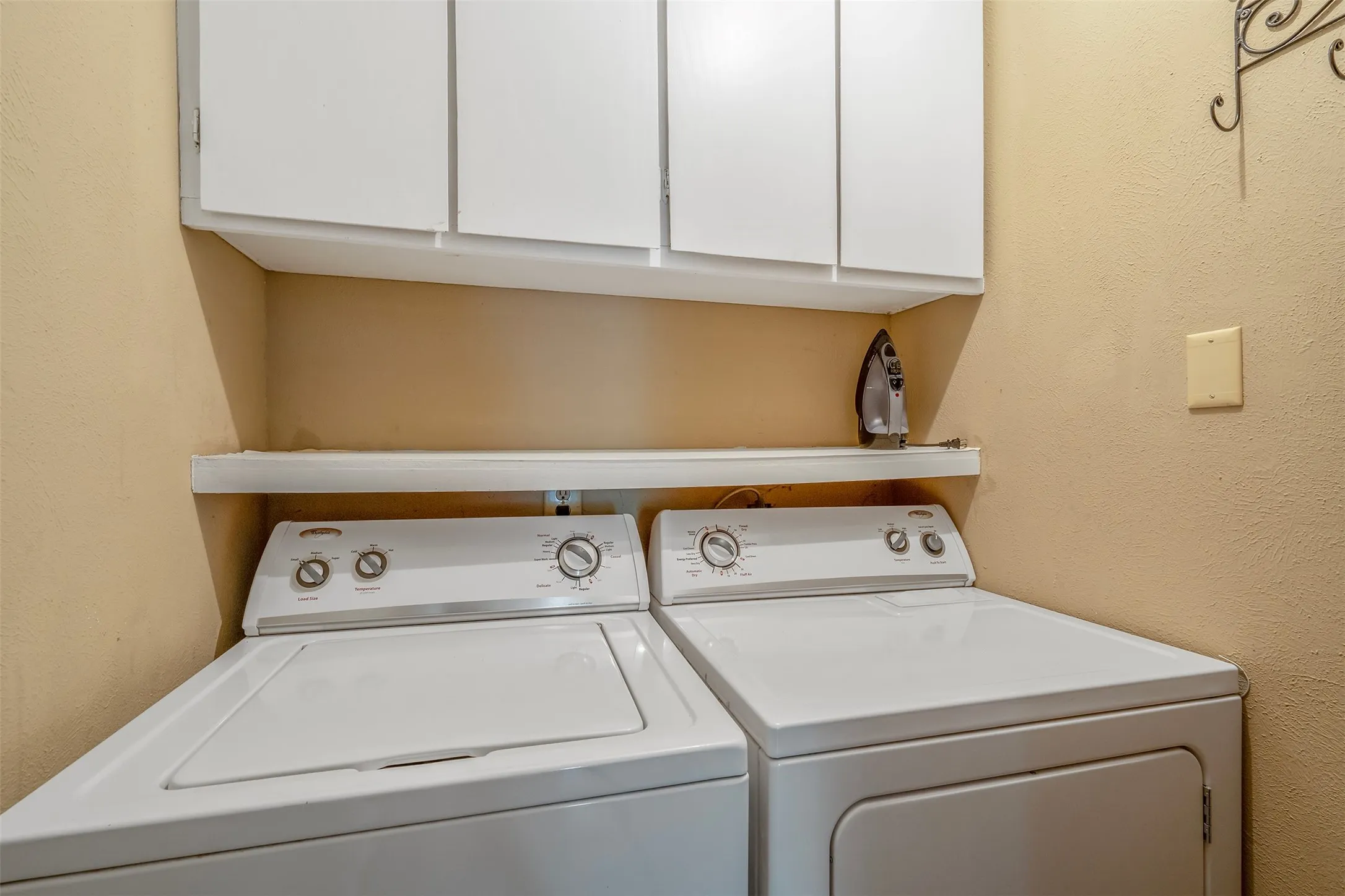 White upper cabinetry, open shelving, and a washer and dryer