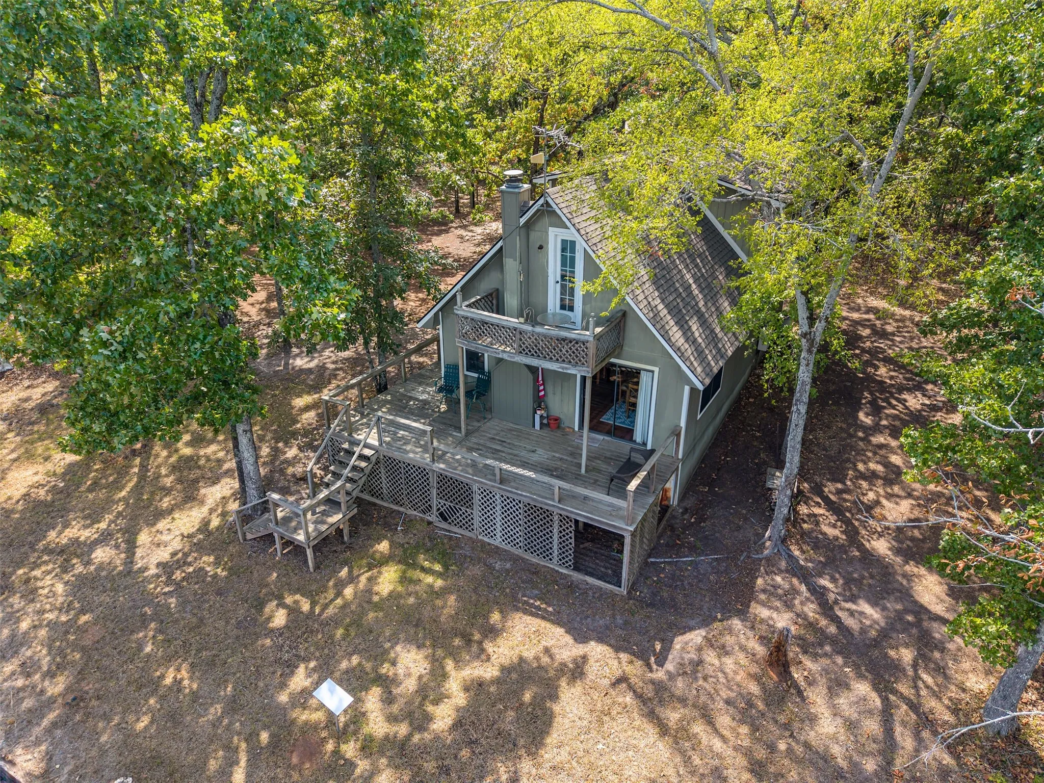Two-story dwelling featuring a gabled roof, prominent chimney, and a multi-level deck with wooden railings