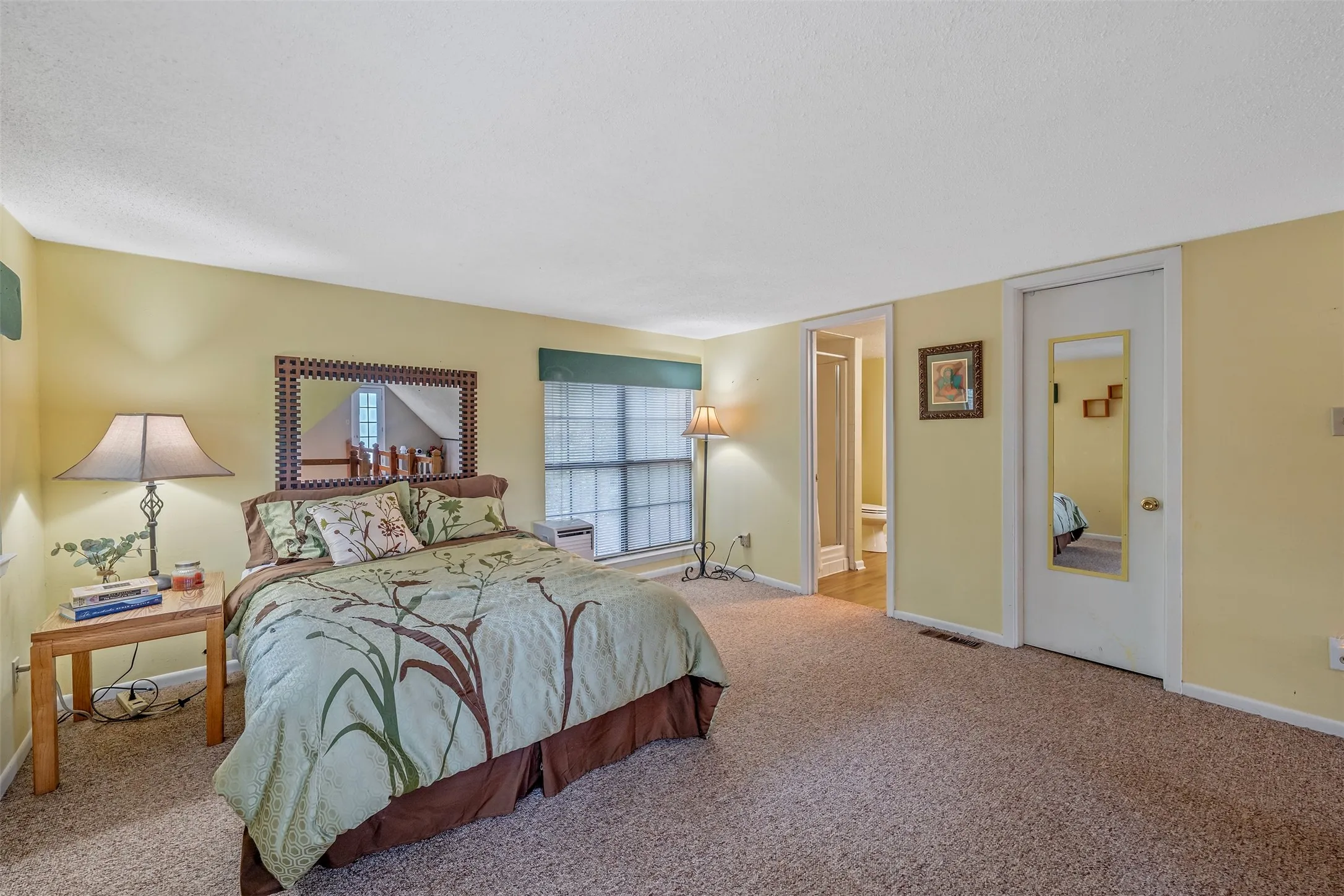 Carpeted flooring extending through the space, light-toned walls, and a window with horizontal blinds