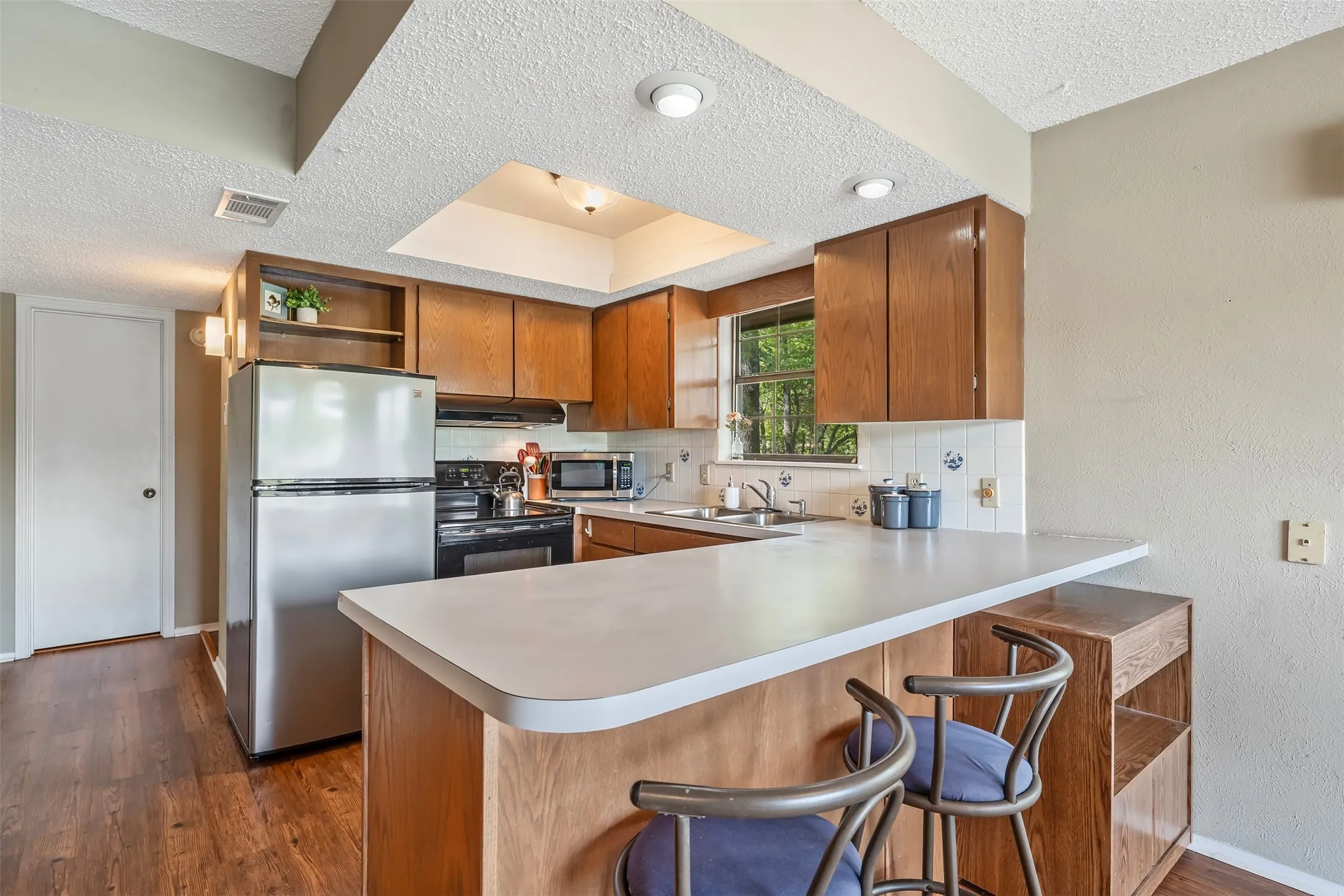 Kitchen featuring wood-finish cabinetry, stainless steel appliances, a breakfast bar, and wood-finish flooring