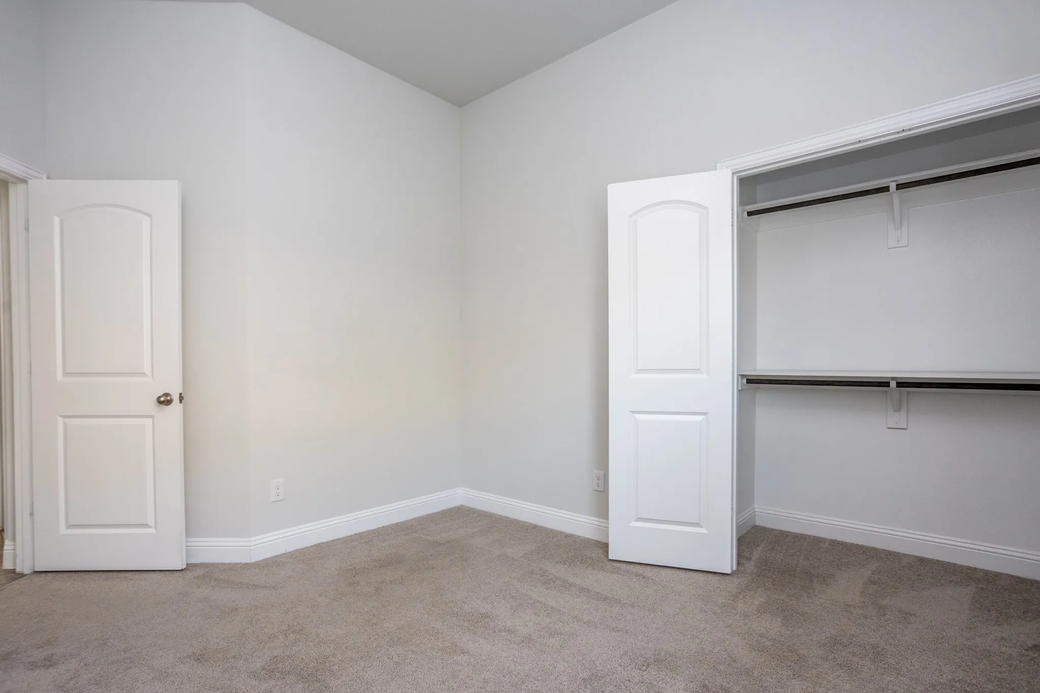 Neutral-toned carpeting, white baseboards, and a two-panel interior door