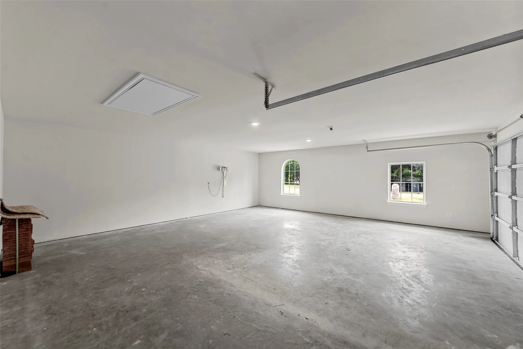 Spacious garage with concrete flooring, recessed lighting, and two windows providing natural illumination