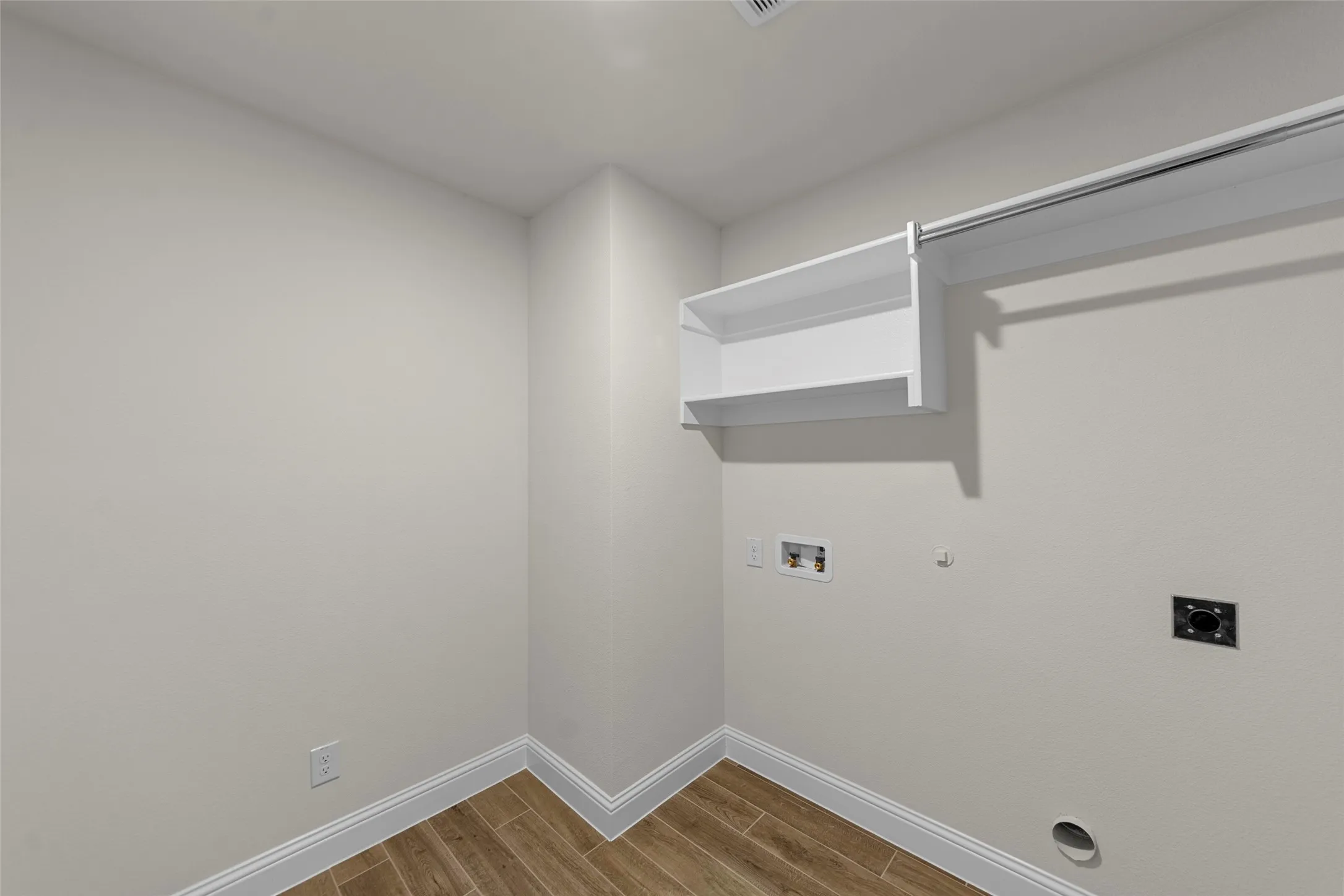 Wood-finish flooring, white built-in shelving, white trim, and light-toned walls