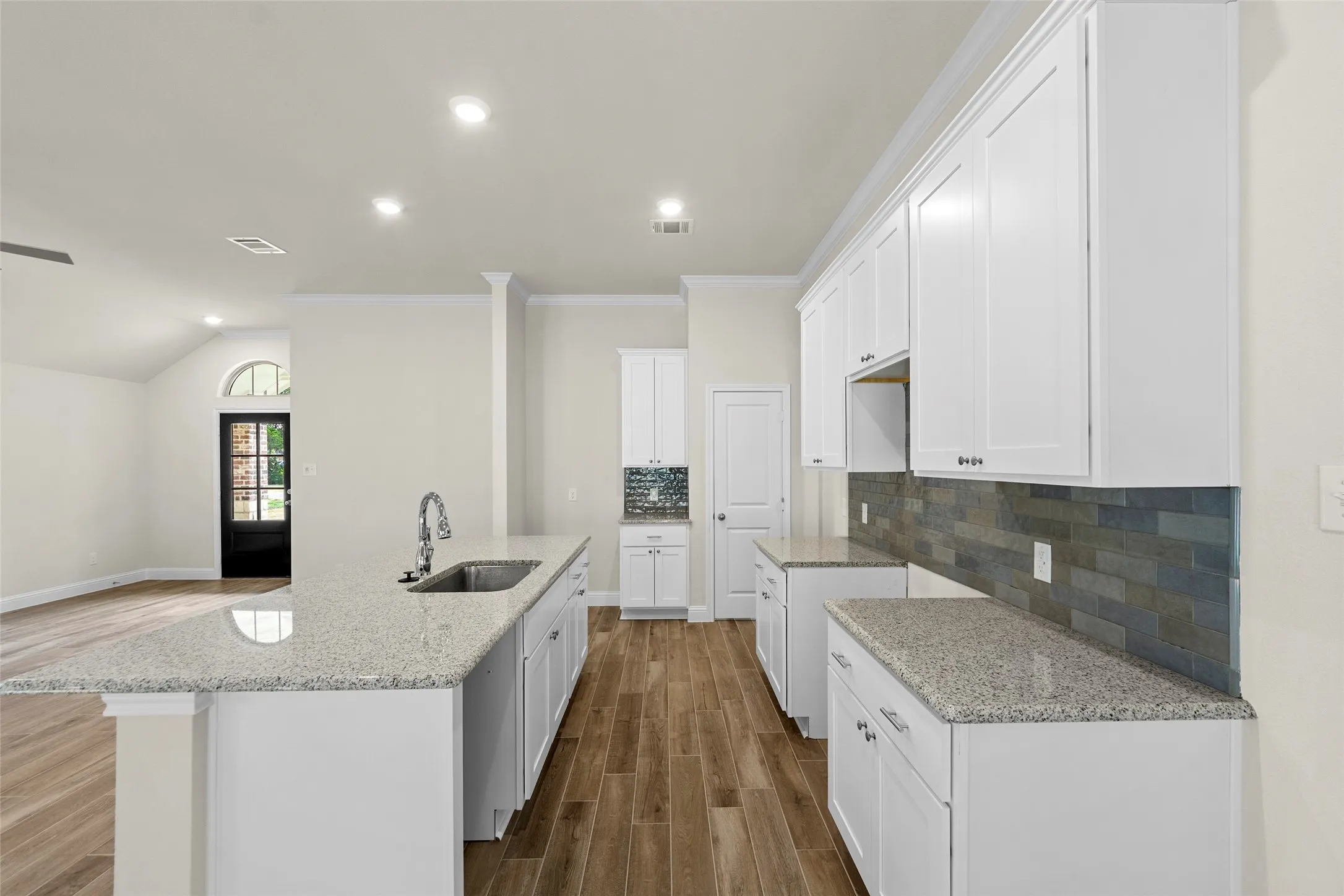 Kitchen featuring white cabinetry, light-toned countertops, subway tile backsplash, and wood-finish flooring