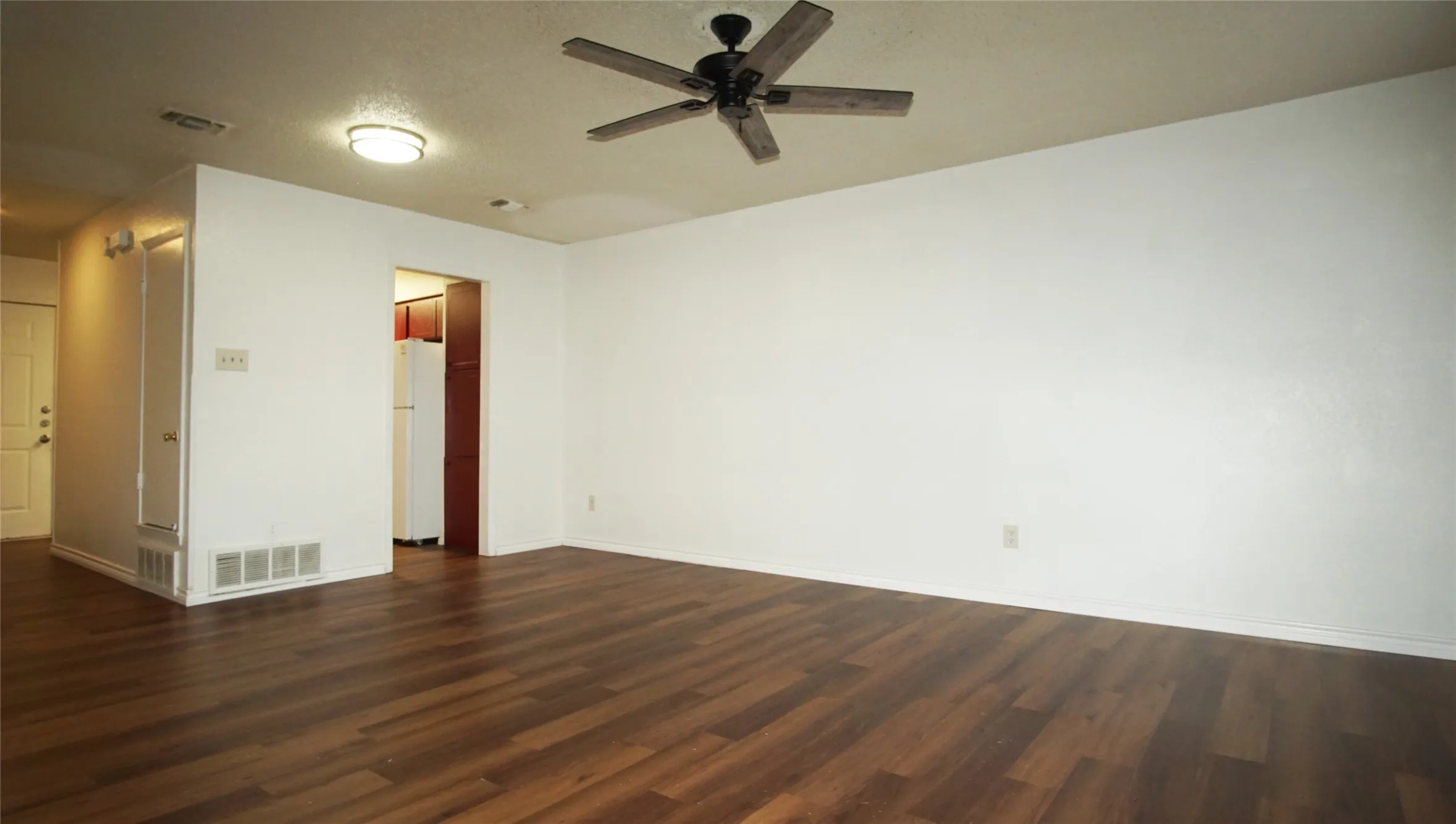 Empty room featuring dark wood-type flooring and a ceiling fan