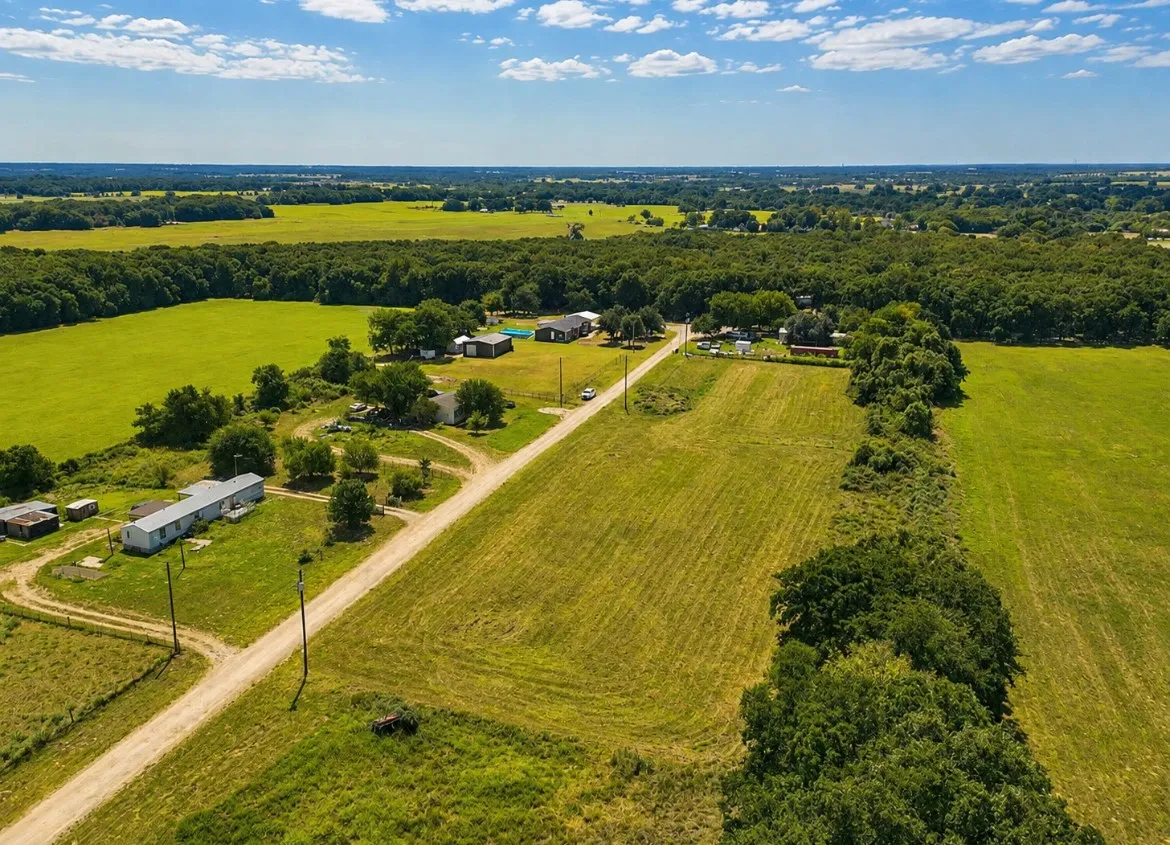 Expansive rural property featuring multiple structures, open pastures, and mature tree lines