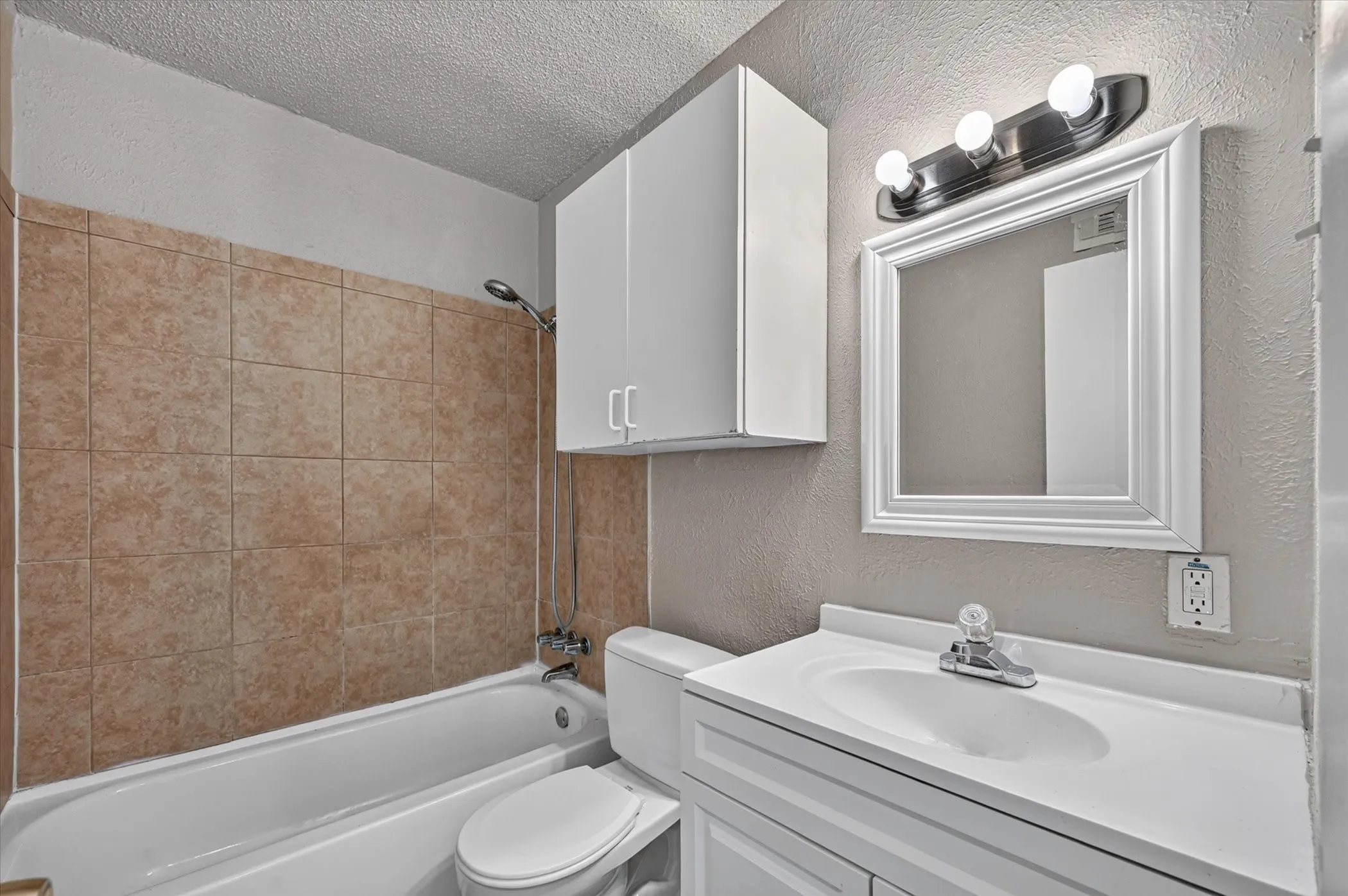 White vanity with integrated sink, white framed mirror, and brushed nickel light fixture