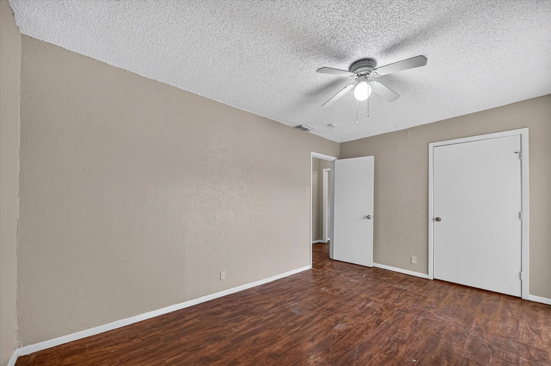 Wood-finish flooring, neutral-toned walls, and a ceiling fan with integrated lighting